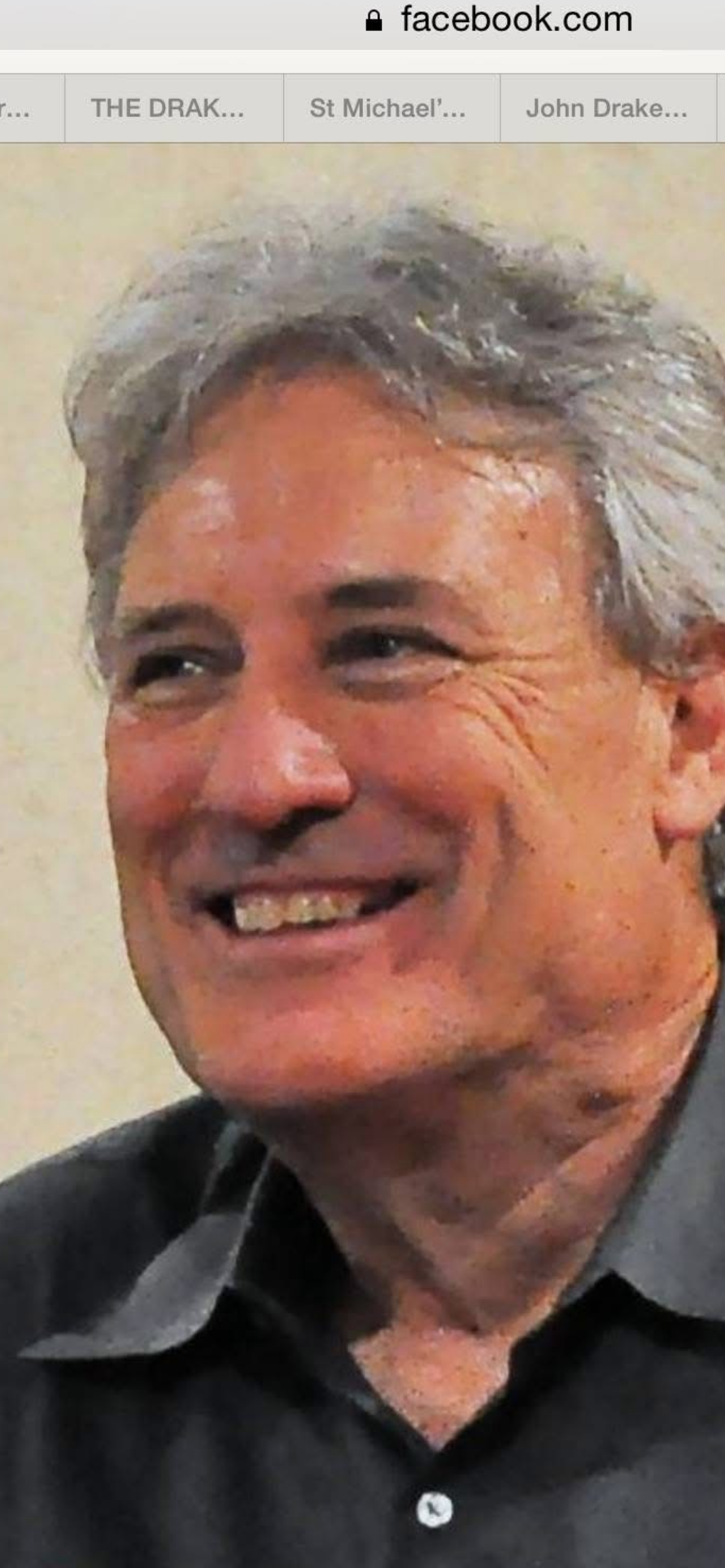 Close-up of a smiling man with gray hair, wearing a dark collared shirt.