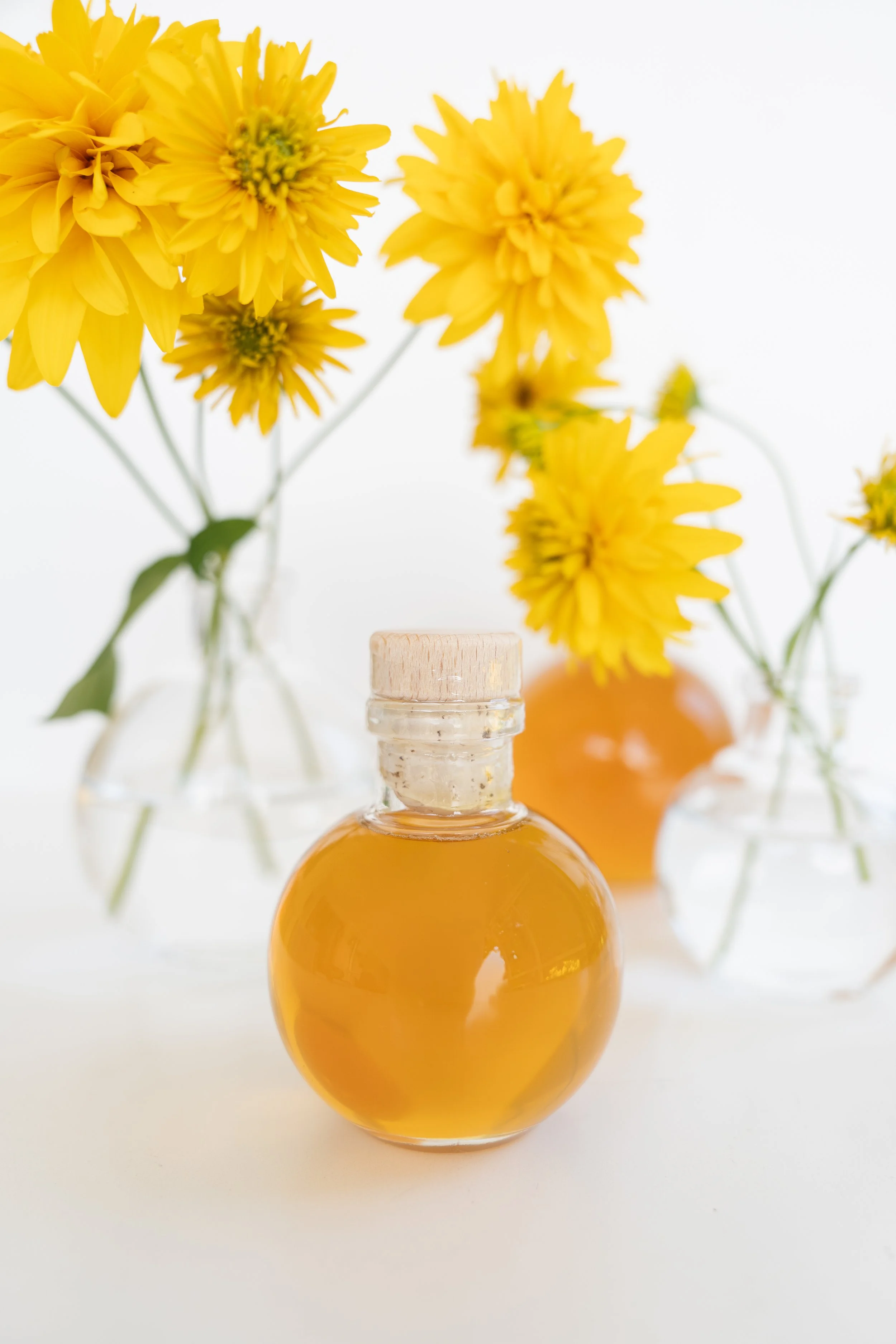 glass bottles of honey and vases with yellow flowers
