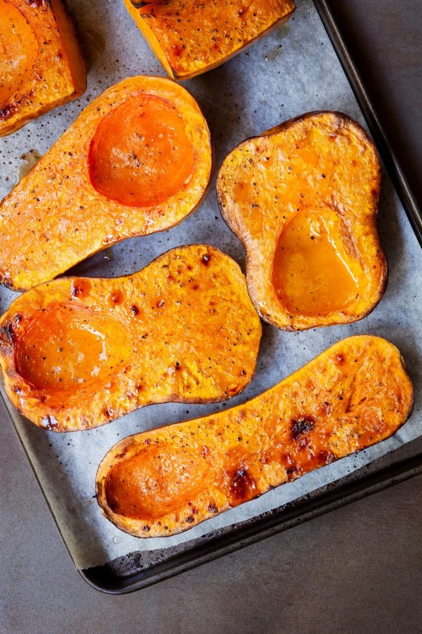 Baked sweet potato halves with runny yolks on a baking sheet.