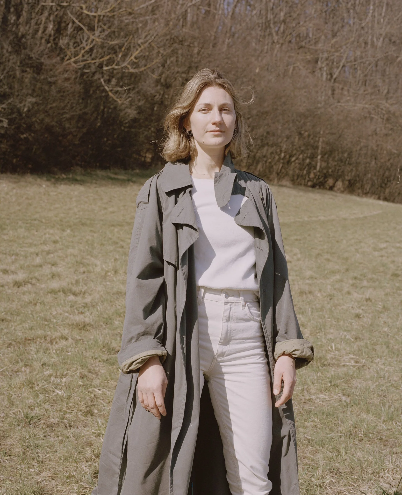 Portraitfotografie einer Frau, die auf einem Feld steht und in die Kamera blickt