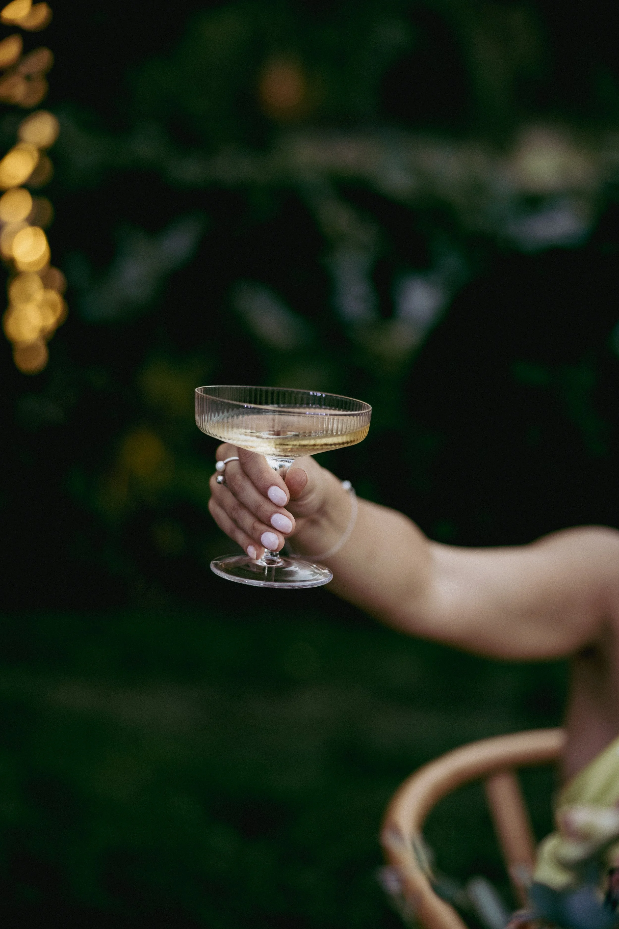 A small champagne coupe held out by a hand