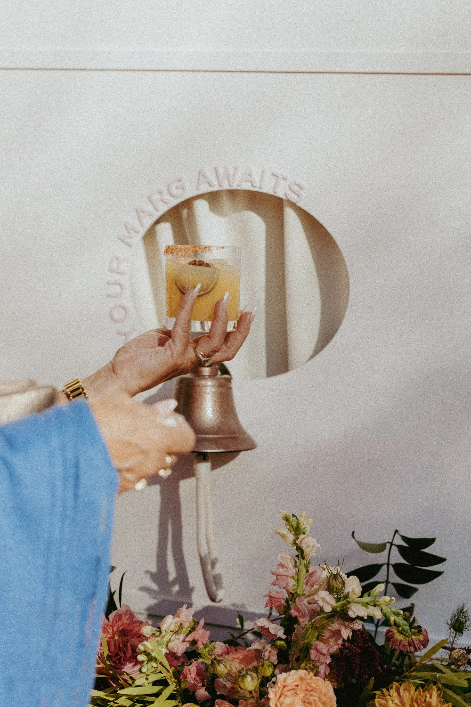 A woman grabbing a drink from a drink wall that says "your marg awaits"