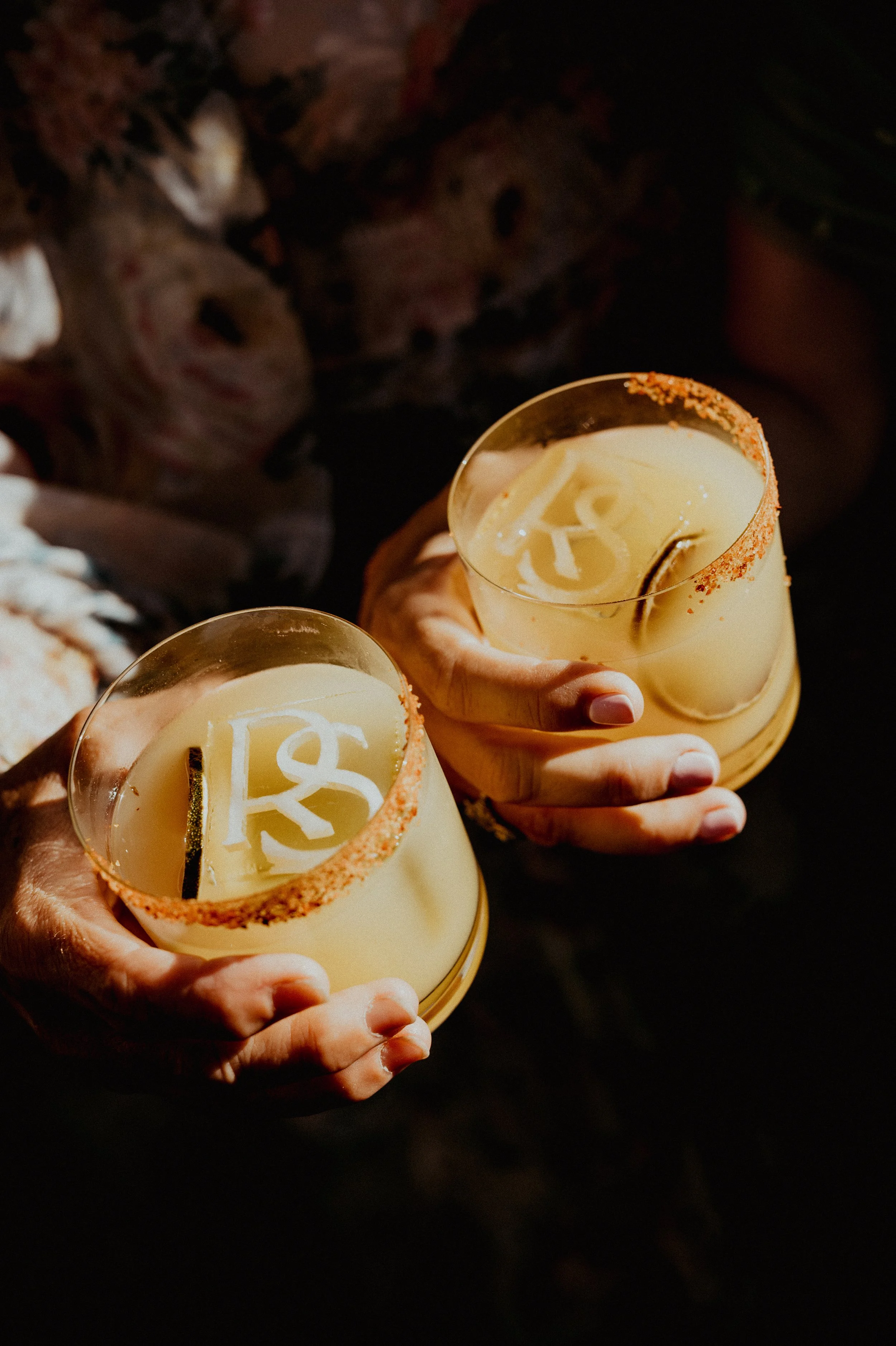 Two margaritas with initials carved into the ice being shown to the camera
