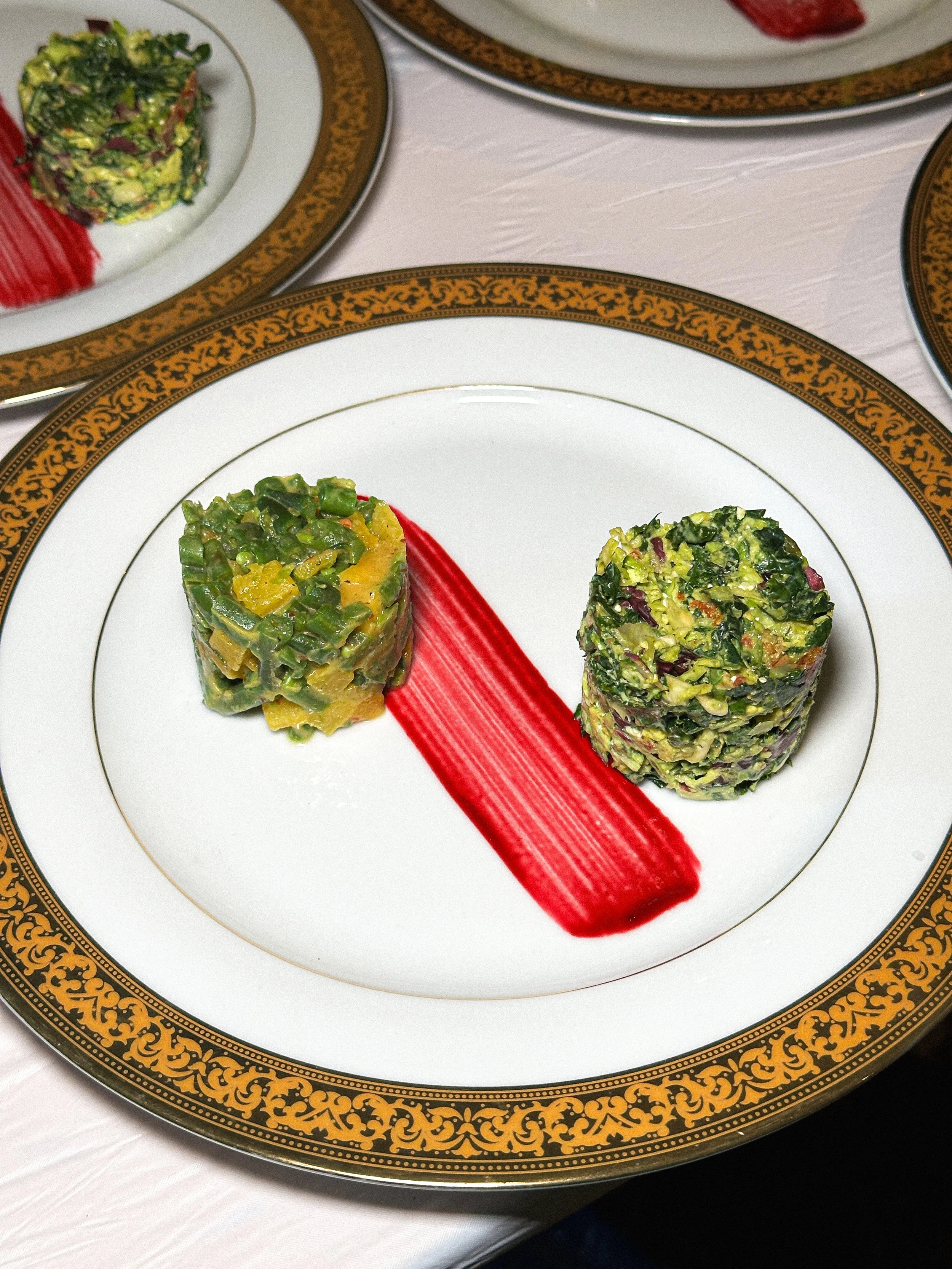 Plate with two cylindrical stacks of chopped vegetables with sauce or puree streak in the middle.