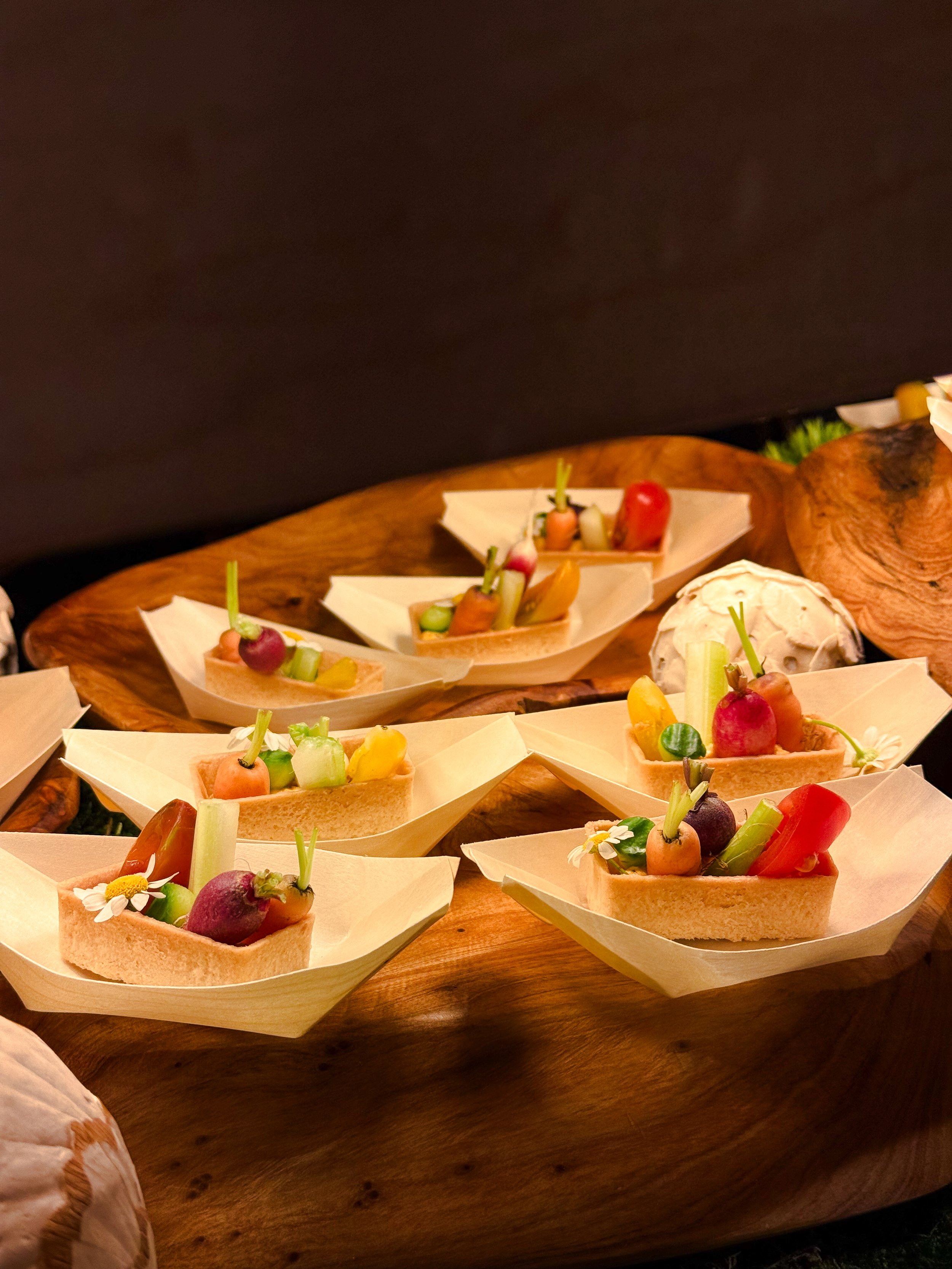 Assorted vegetable toothpicks on small bread slices served on a wooden platter.