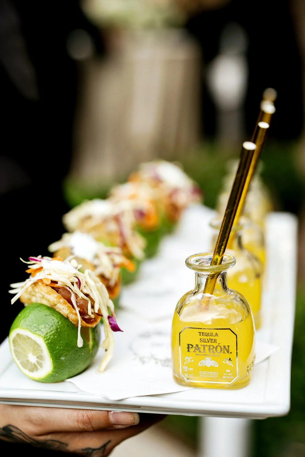 Mini tacos sitting on top of a lime with a mini margarita inside of a mini patron bottle