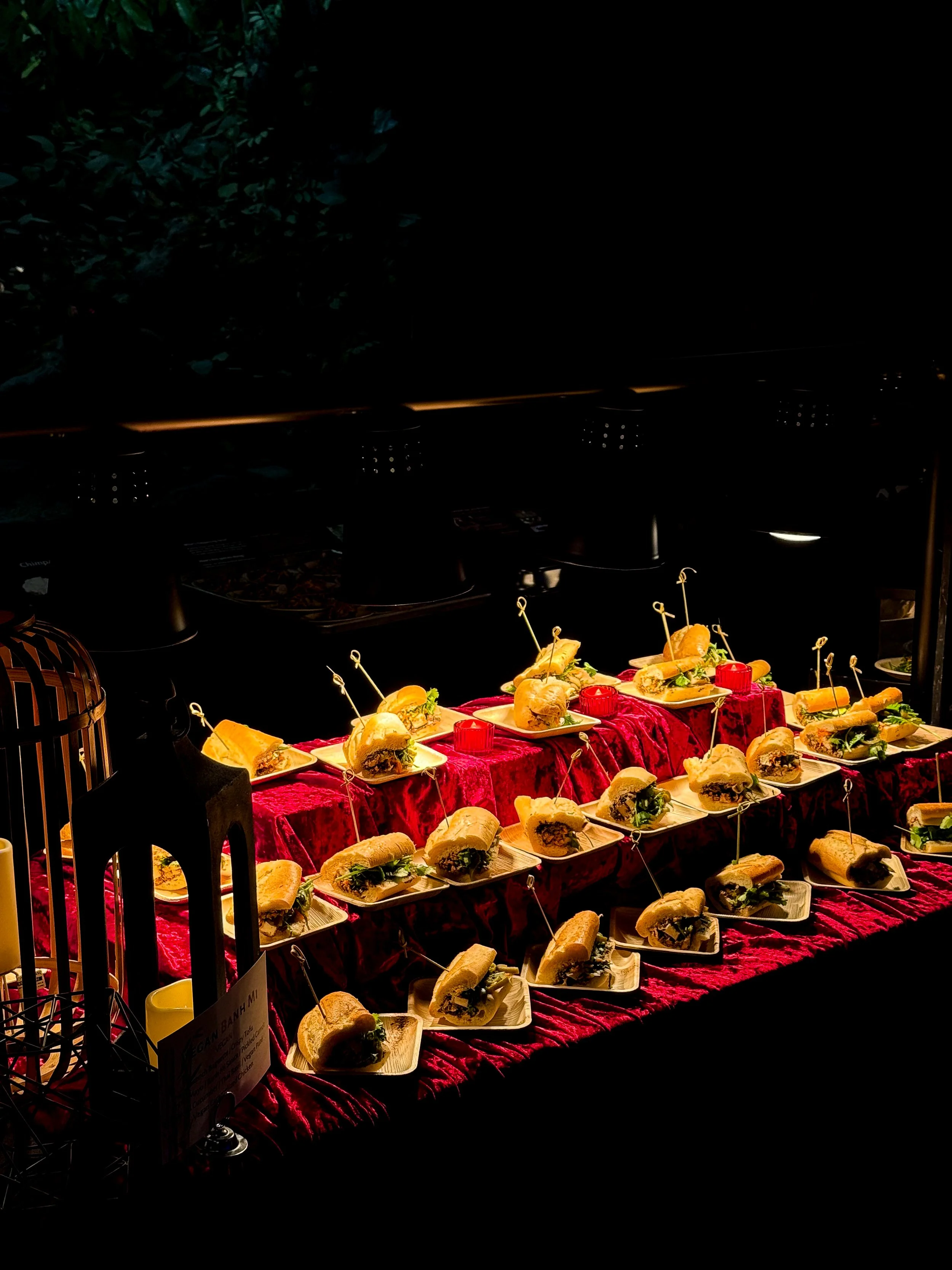 Sandwiches sitting on top of a red velvet cloth, lit up by warming lights