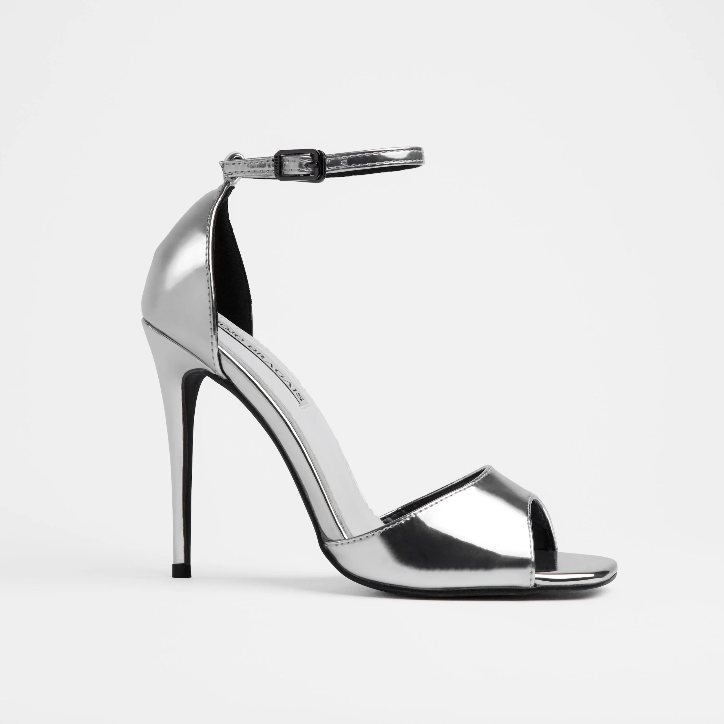 A metalic silver high-heeled stiletto pageant shoe with an ankle strap and heel cap, photographed against a plain white background.