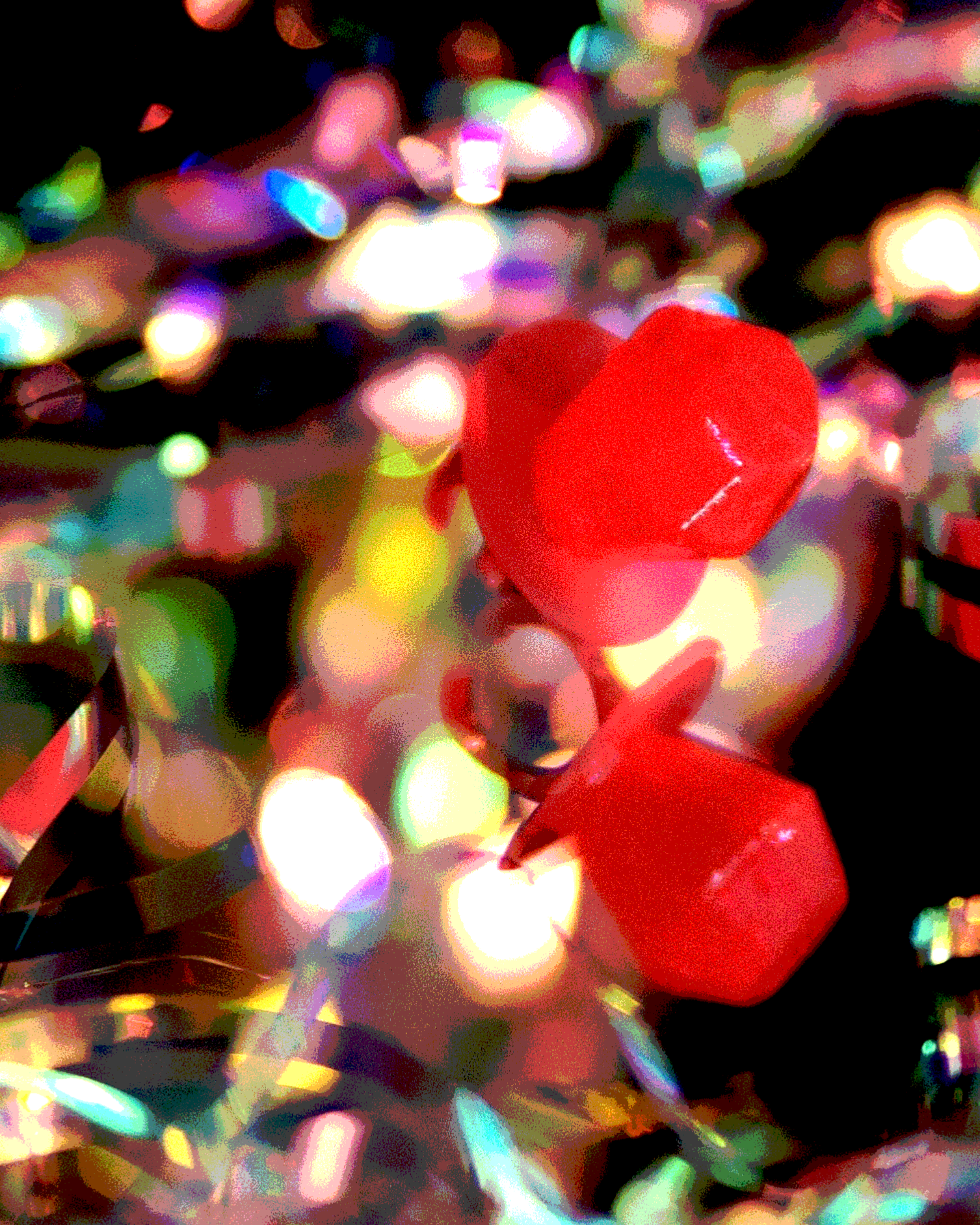Close-up of colorful, iridescent confetti and a red Ring Pop against its own reflection.