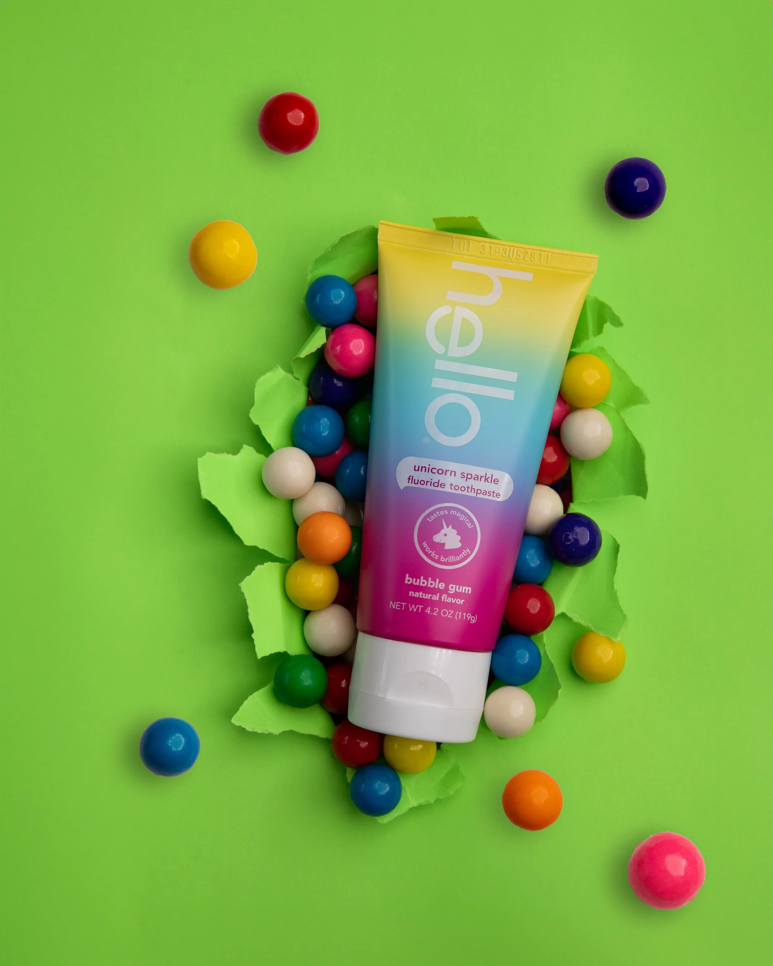 Colorful bubble gum toothpaste tube with multicolored gumballs on bright green background.