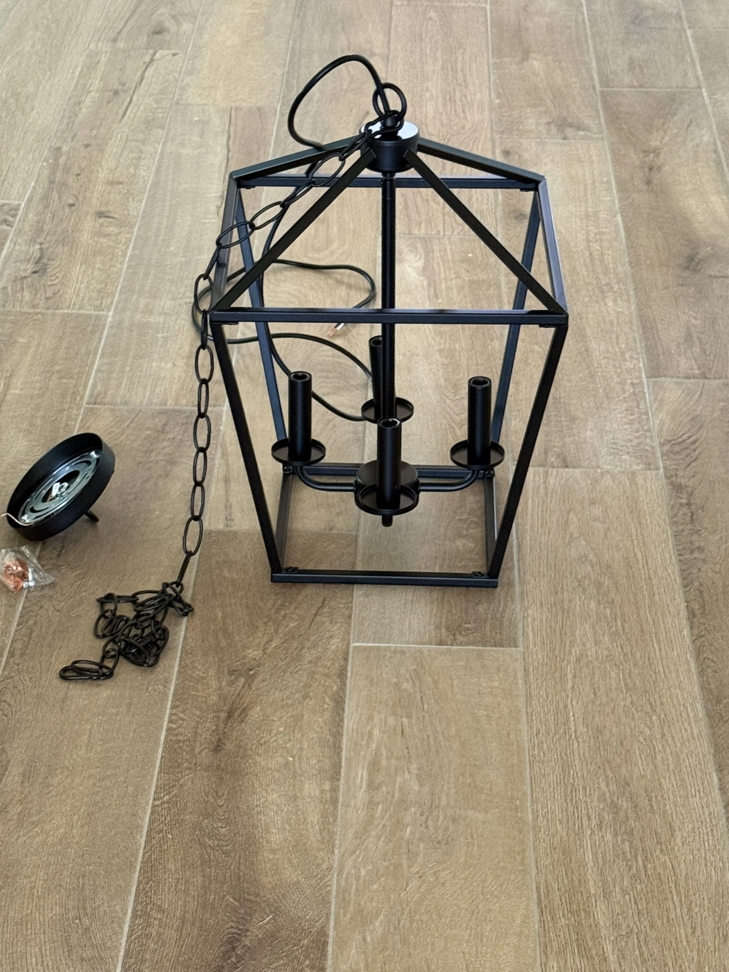 Black cage-style lantern light fixture staged for installation during a home lighting upgrade by MZL Construction in Dallas-Fort Worth