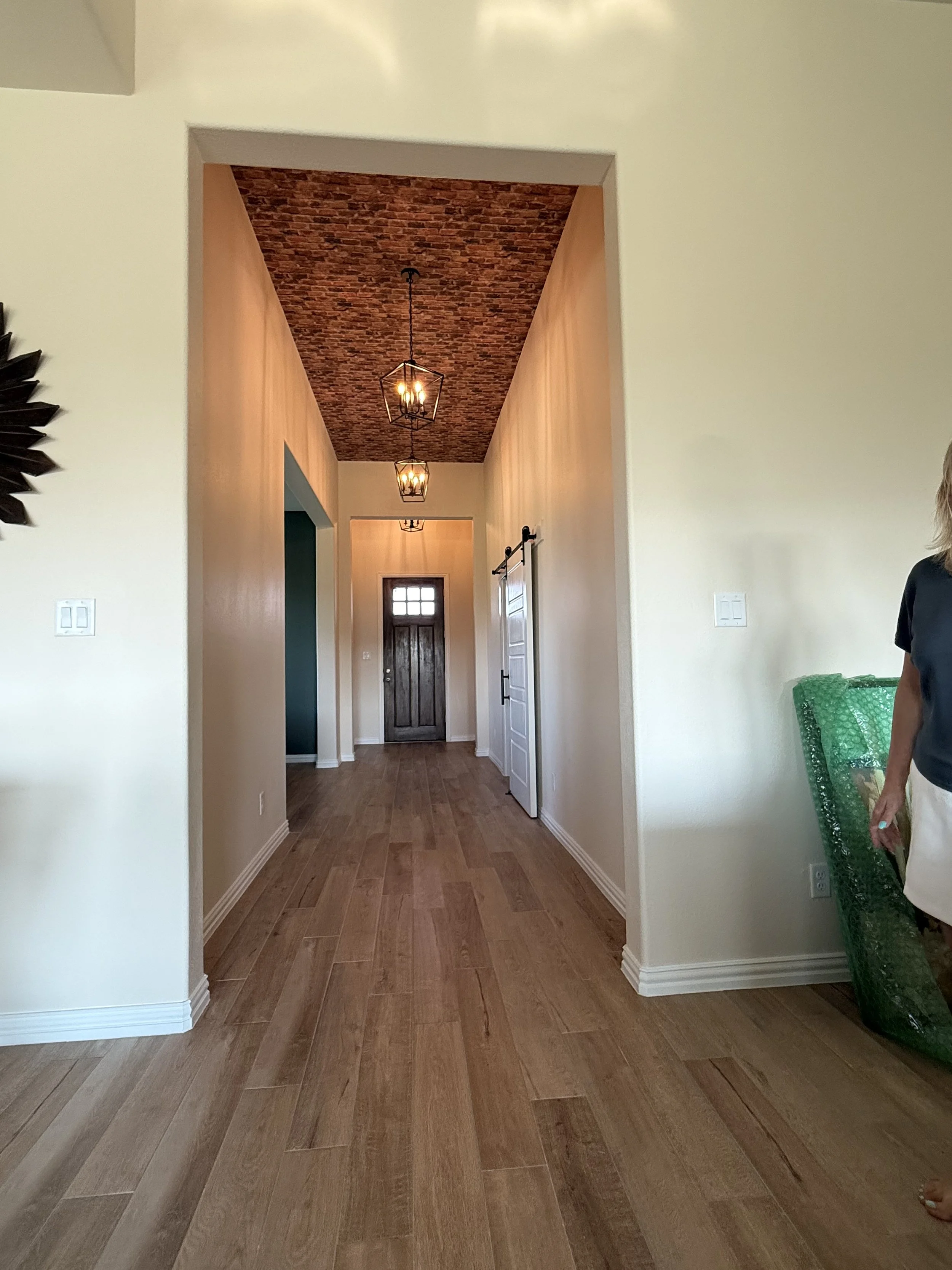 Wide view down a renovated hallway with wood-look plank flooring and brick-accent ceiling, home improvement project completed by MZL Construction