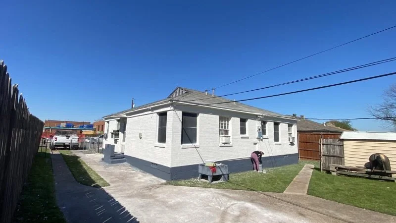 After: the same home freshly painted white with navy-blue trim by MZL Construction, completing a full exterior repaint in the Dallas-Fort Worth Metroplex
