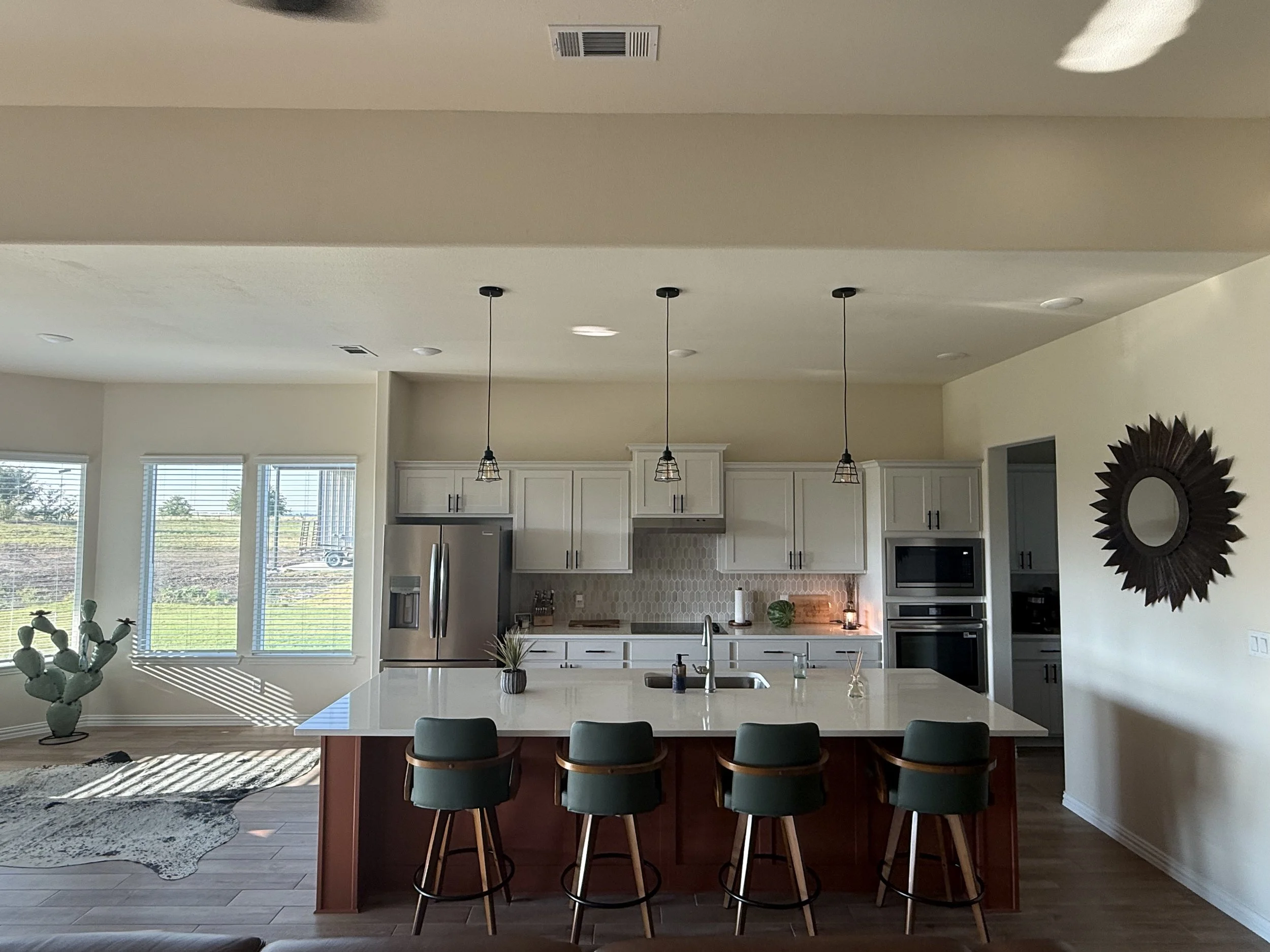 Remodeled kitchen with white shaker cabinets, quartz island, green velvet bar stools, and stainless steel appliances, a full kitchen renovation by MZL Construction in Dallas-Fort Worth