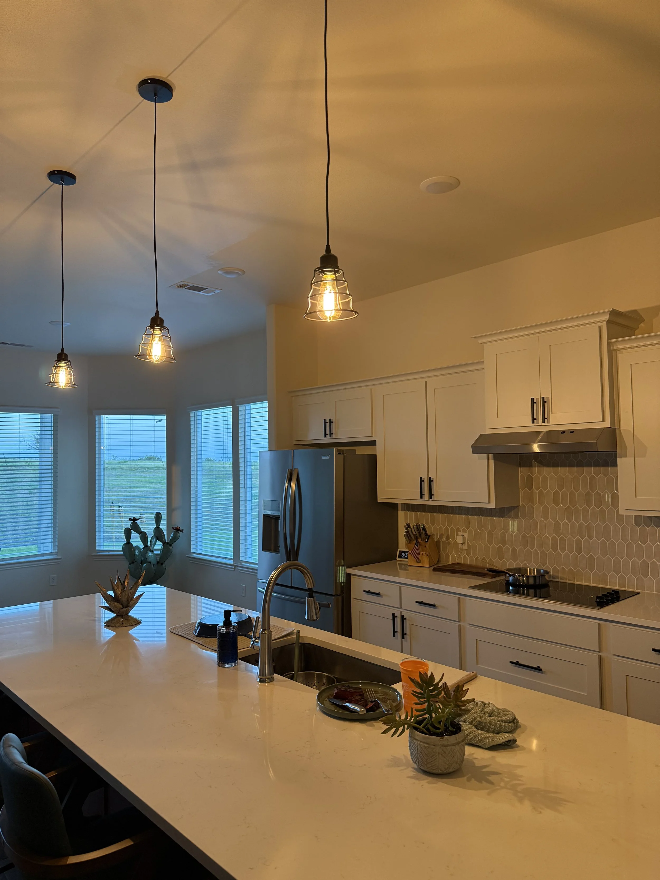 Kitchen island with new pendant lighting and quartz countertops in a Dallas-Fort Worth home renovated by MZL Construction