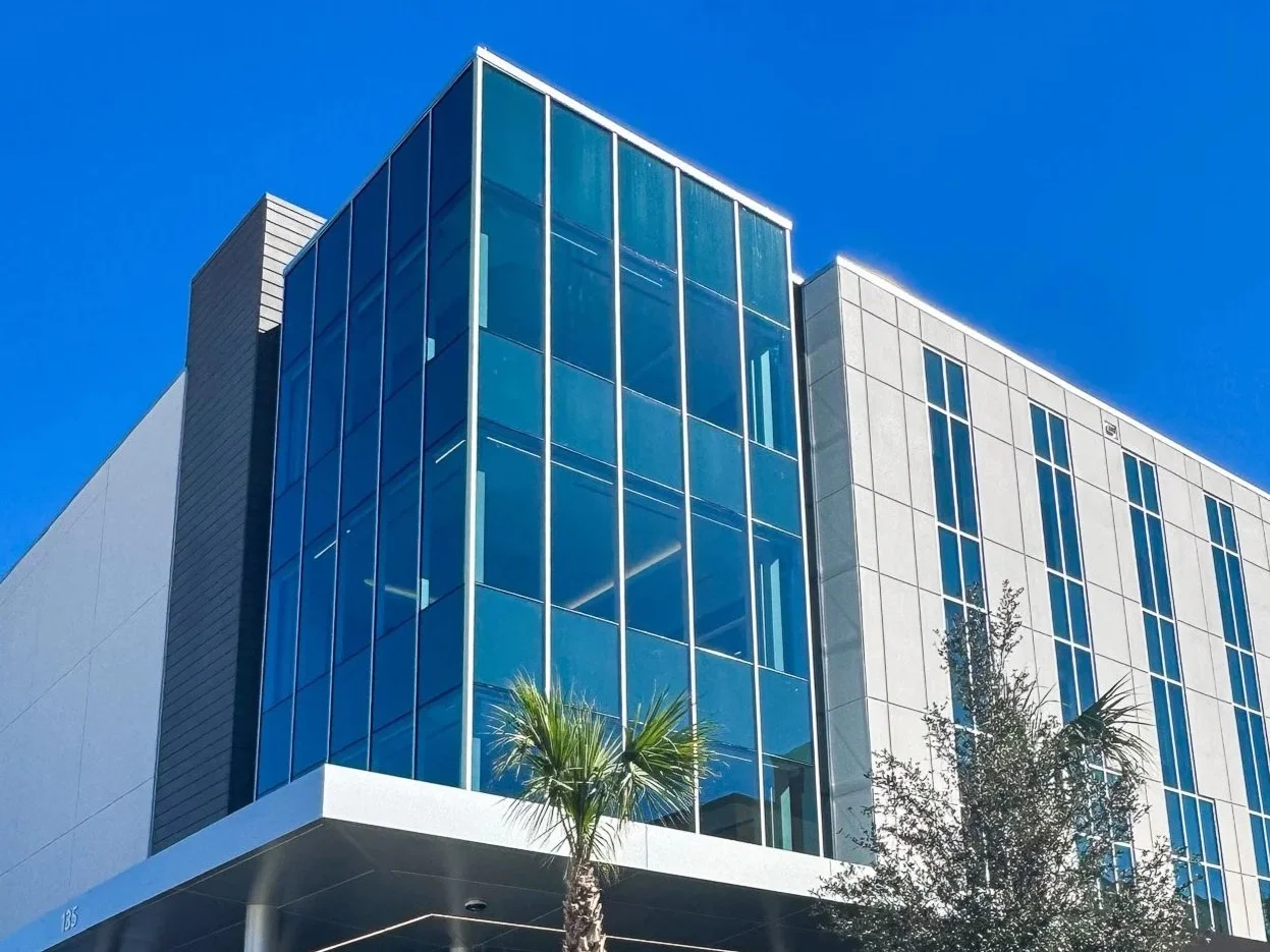 Modern glass office building with palm trees and blue sky