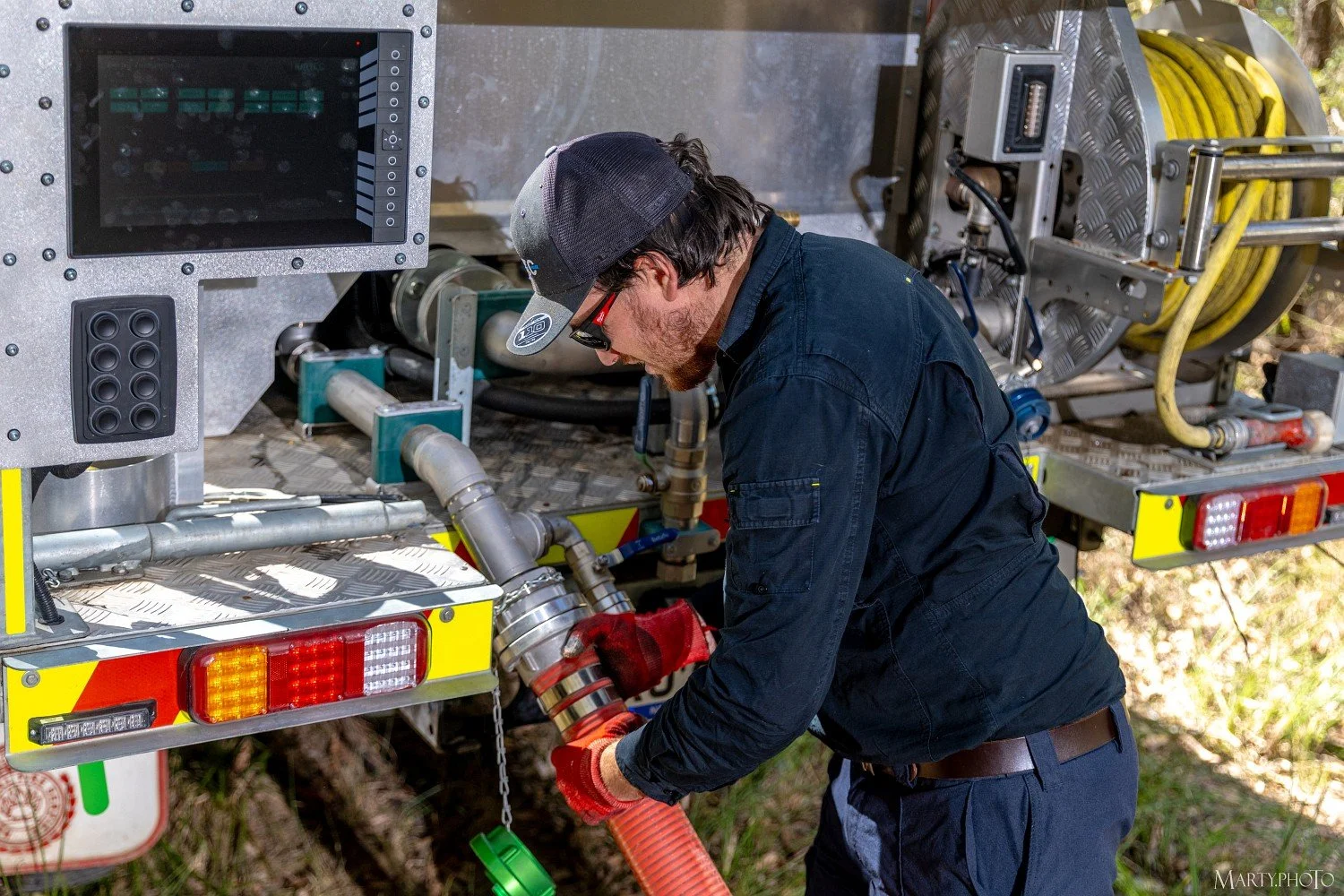 One of Hurtec's expert team working on a fire truck's firefighting hose equipment. He is connecting a large orange drafting hose to the truck. Hurtec's software driven electric pump has one button auto-drafting. Simple, fast and safe.