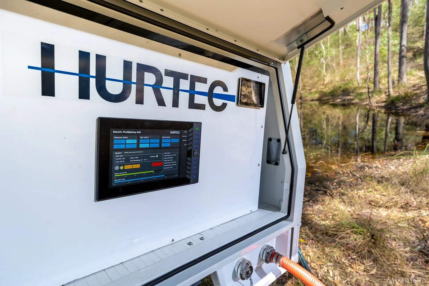 A white mobile unit with the word 'HURTEC' displayed on the side, equipped with a touchscreen interface and some hoses, located outdoors near a wooded area.