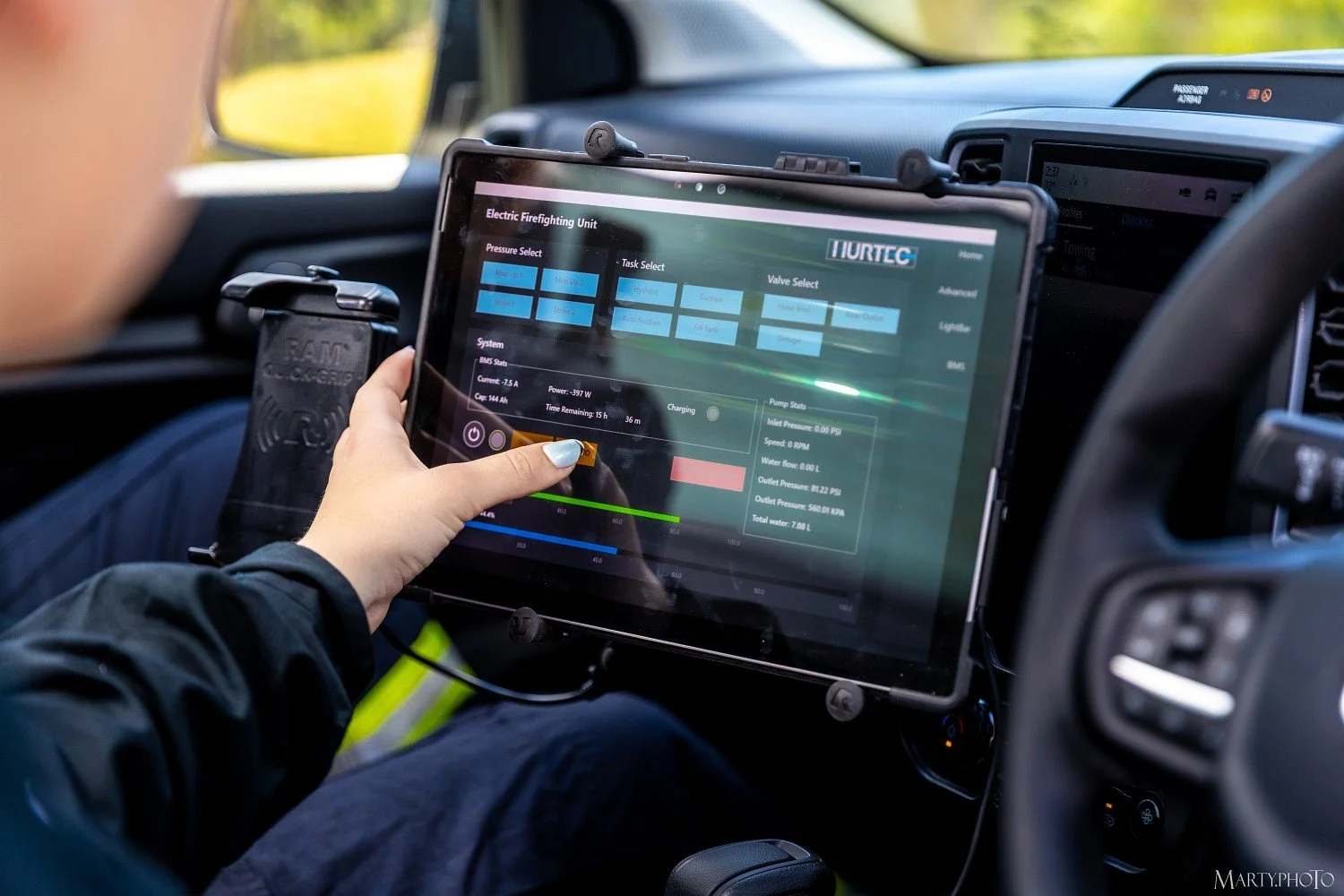 Person using FleetCon on a tablet in a vehicle that is displaying a control interface for an electric firefighting unit and vehicle data.