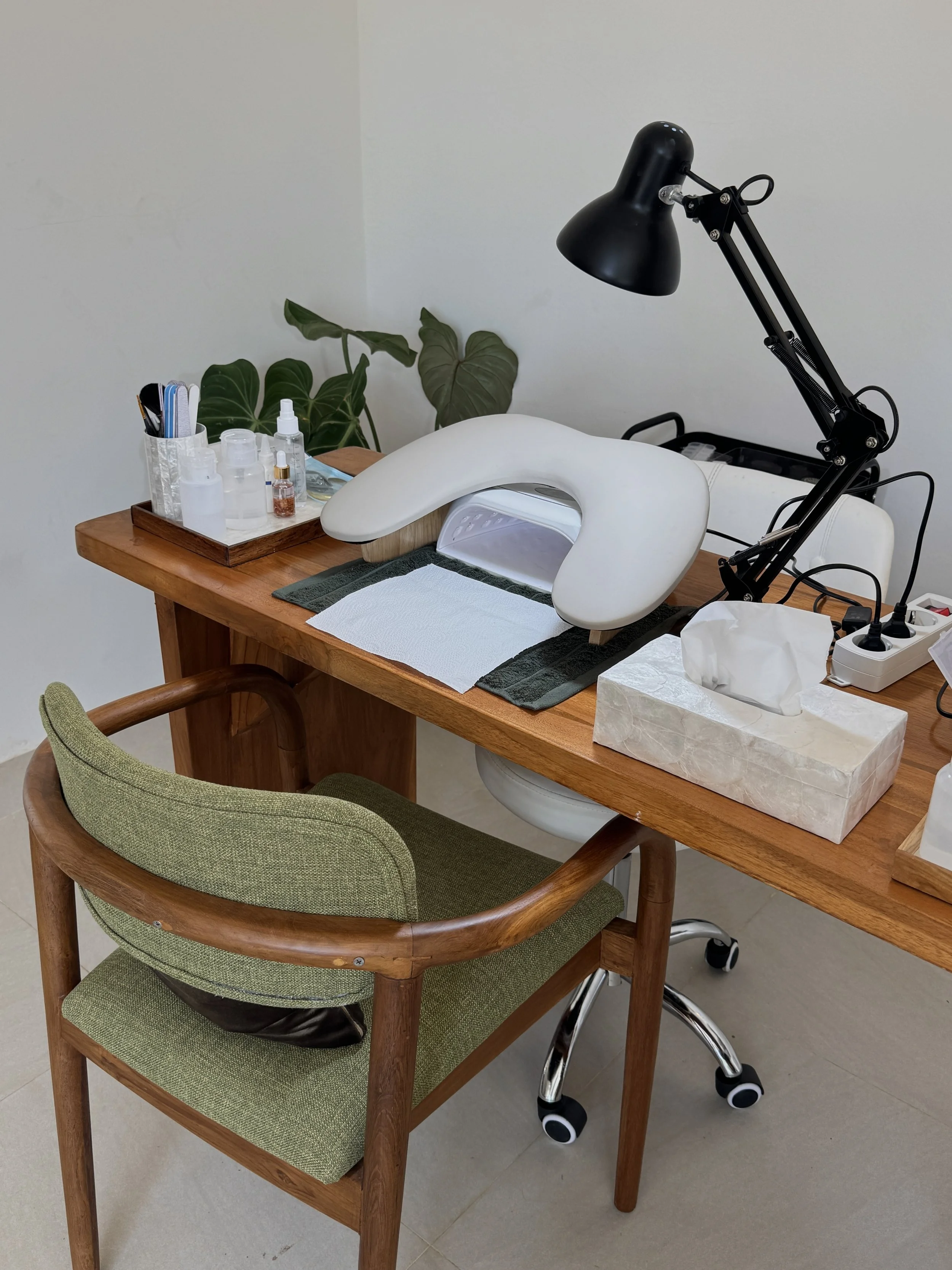 A table with various skincare or beauty tools, a lamp, a plant in the background, tissues, and a specialized skincare device.