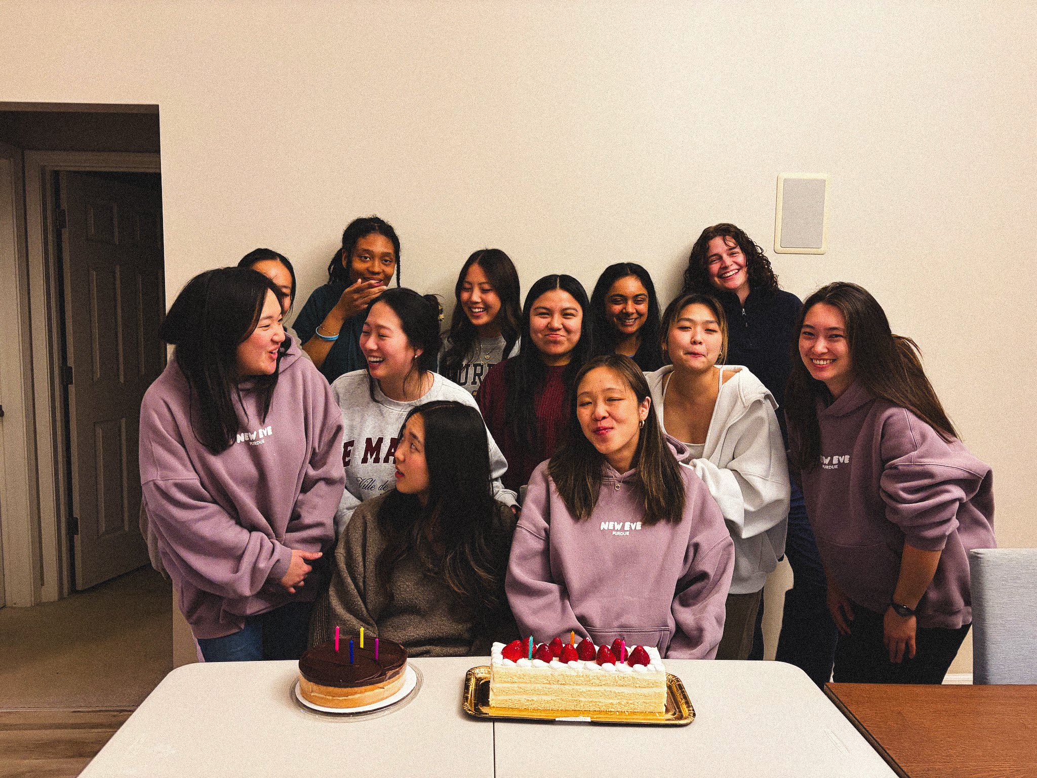 Group of diverse young women and a girl celebrating with cakes and a birthday party, indoors.