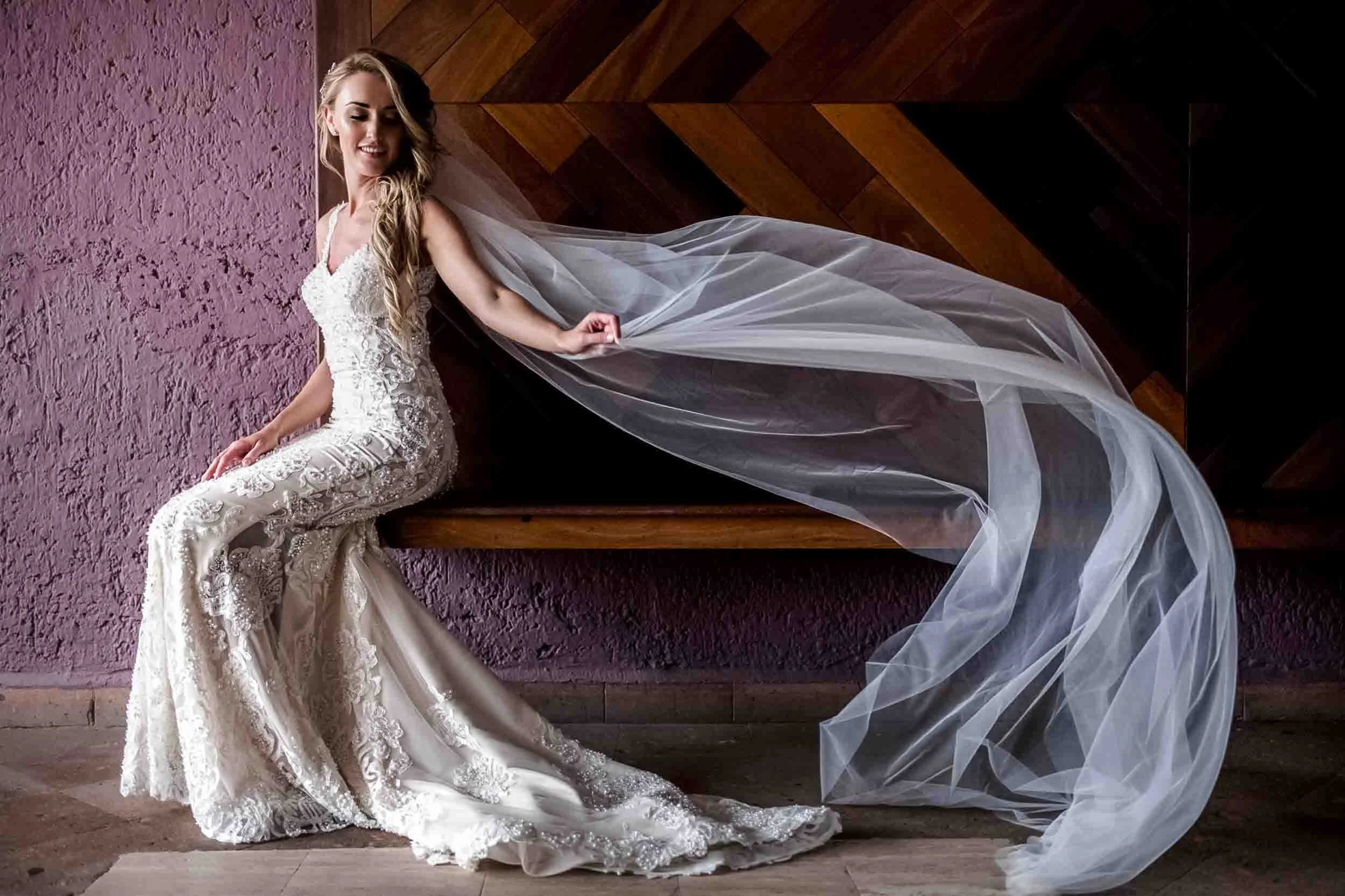 Bridal portrait of bride sitting down and her long veil flying with the wind. 