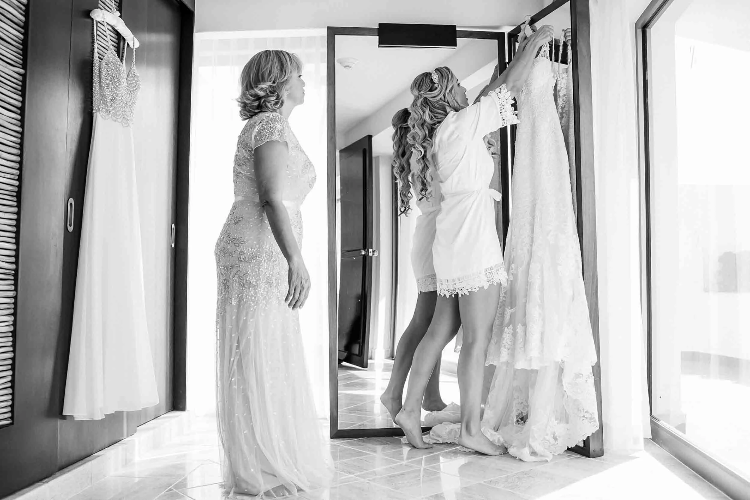 Bride about to get into her wedding dress with her mom at her side. 
