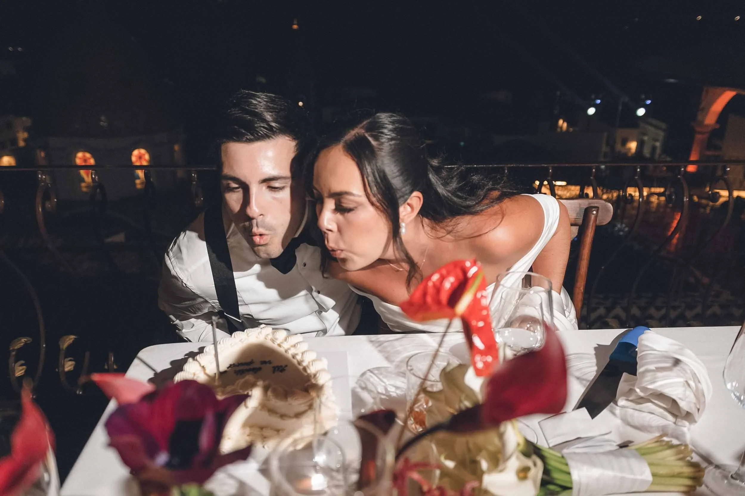 Bride and groom blowing candles on cake during their wedding reception. 