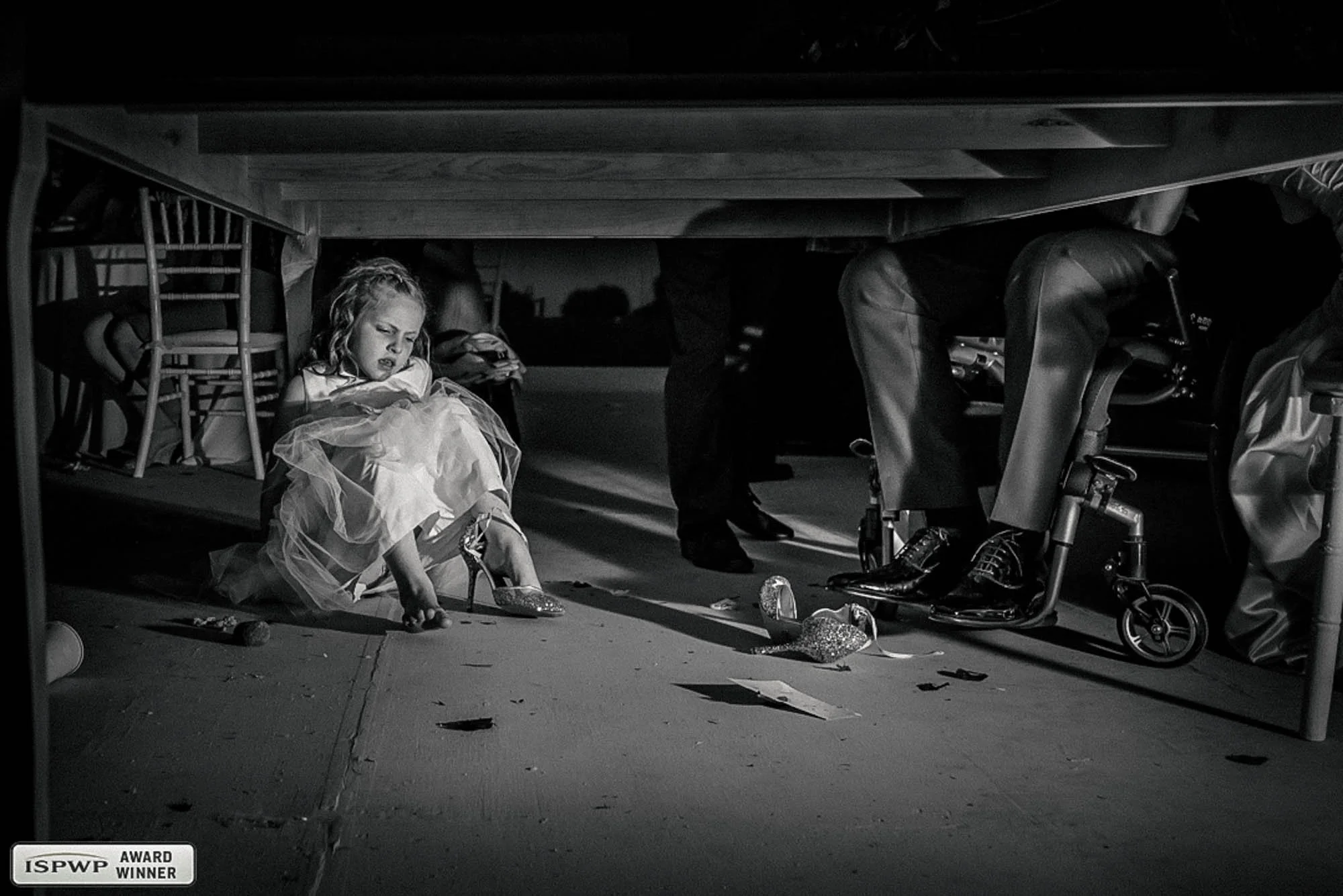 Little girl stealing the shoes of the bride under the table.