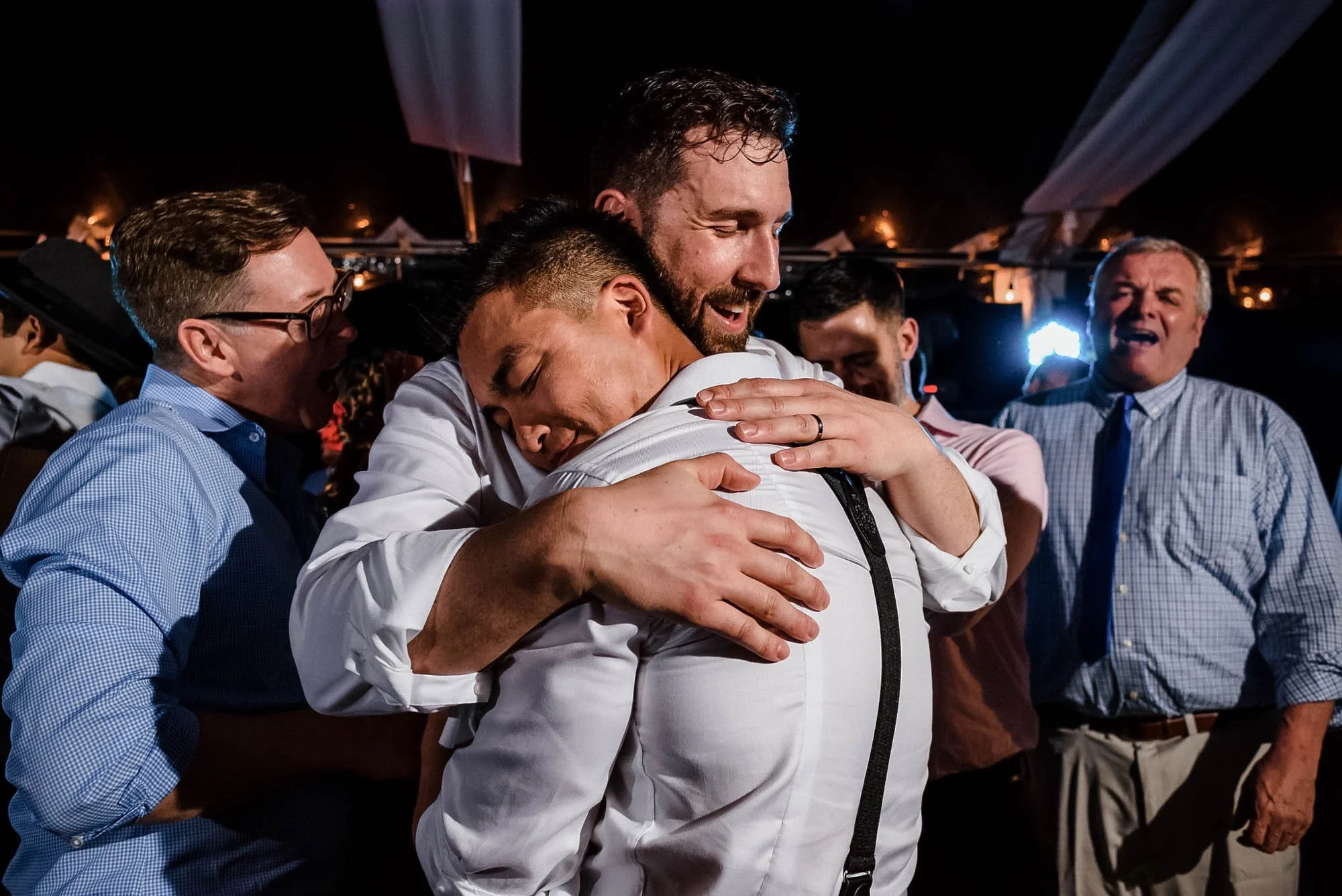 Grooms lovingly hugging on the dance floor during the reception of their beach wedding.