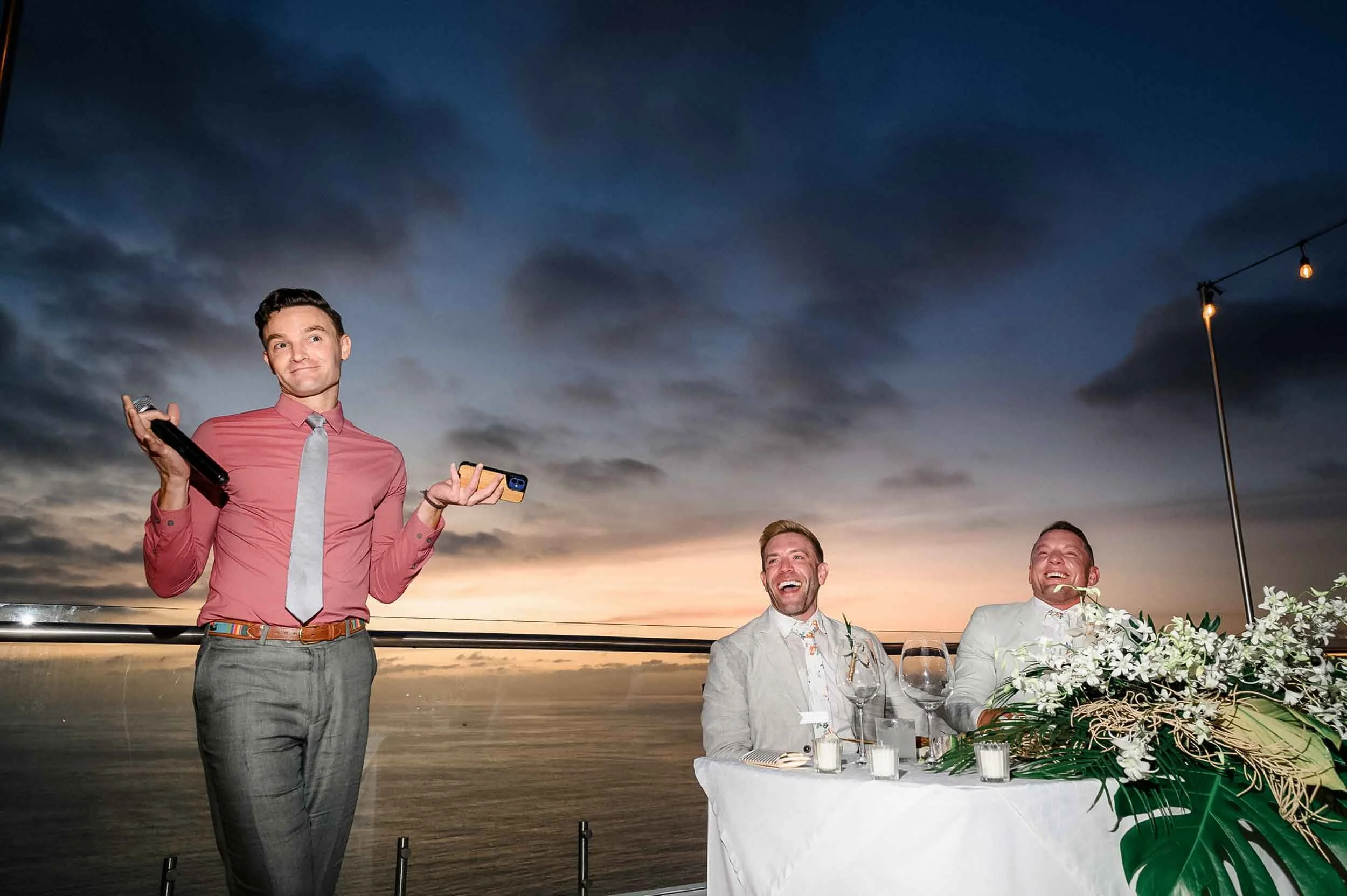 Fun speeches during a lgbtq wedding reception during sunset  with grooms smiling.