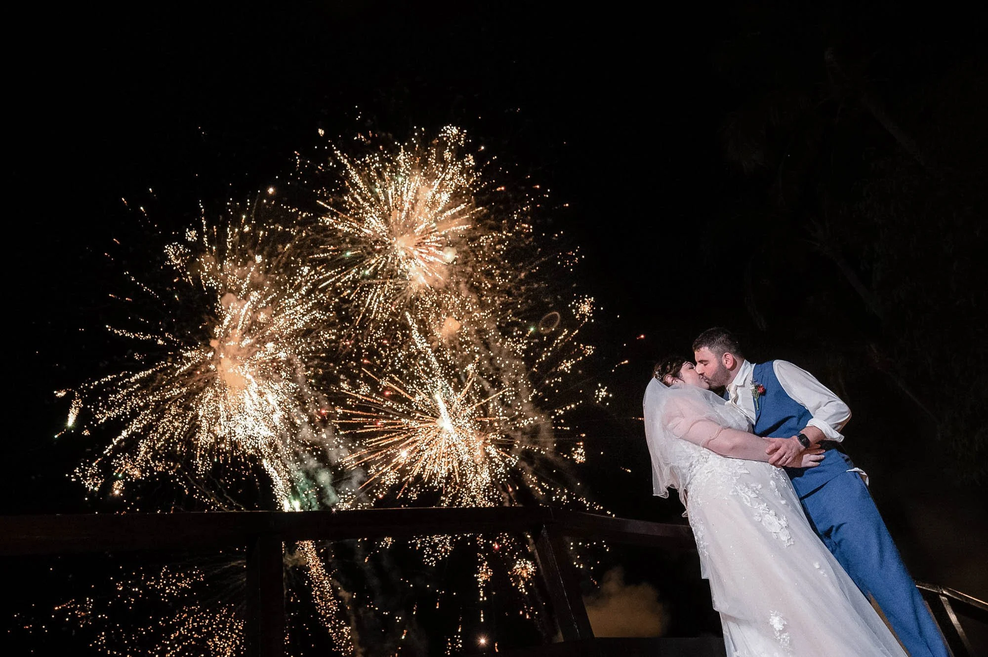 Just married couple kissing with fireworks in the background.
