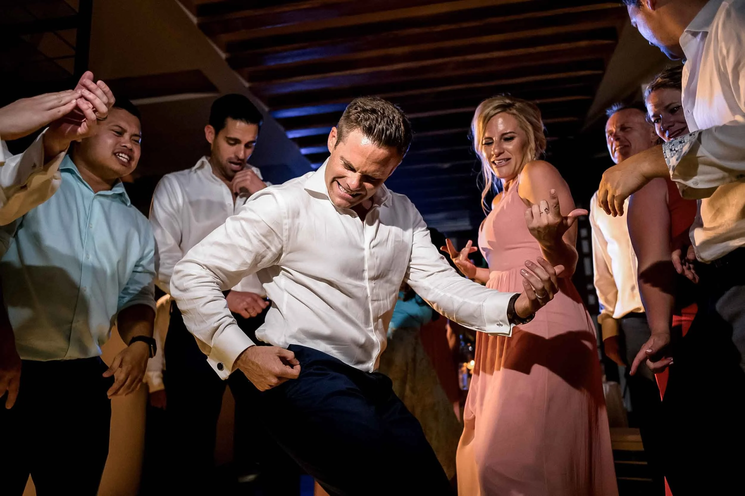 Group of people dancing together at a wedding celebration, smiling and enjoying the moment.