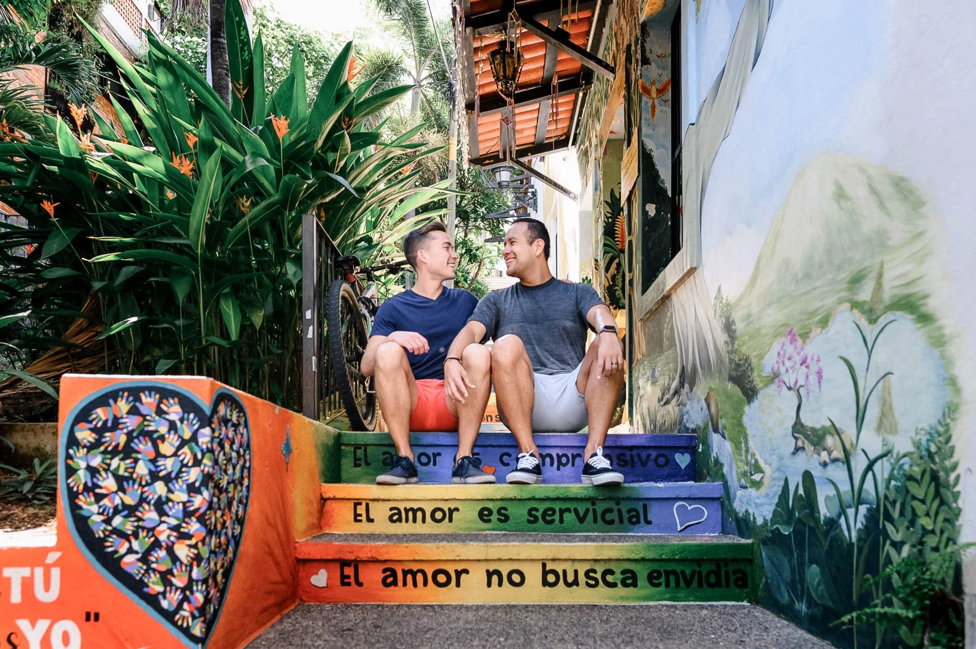 gay couple sitting on rainbow painted stairs