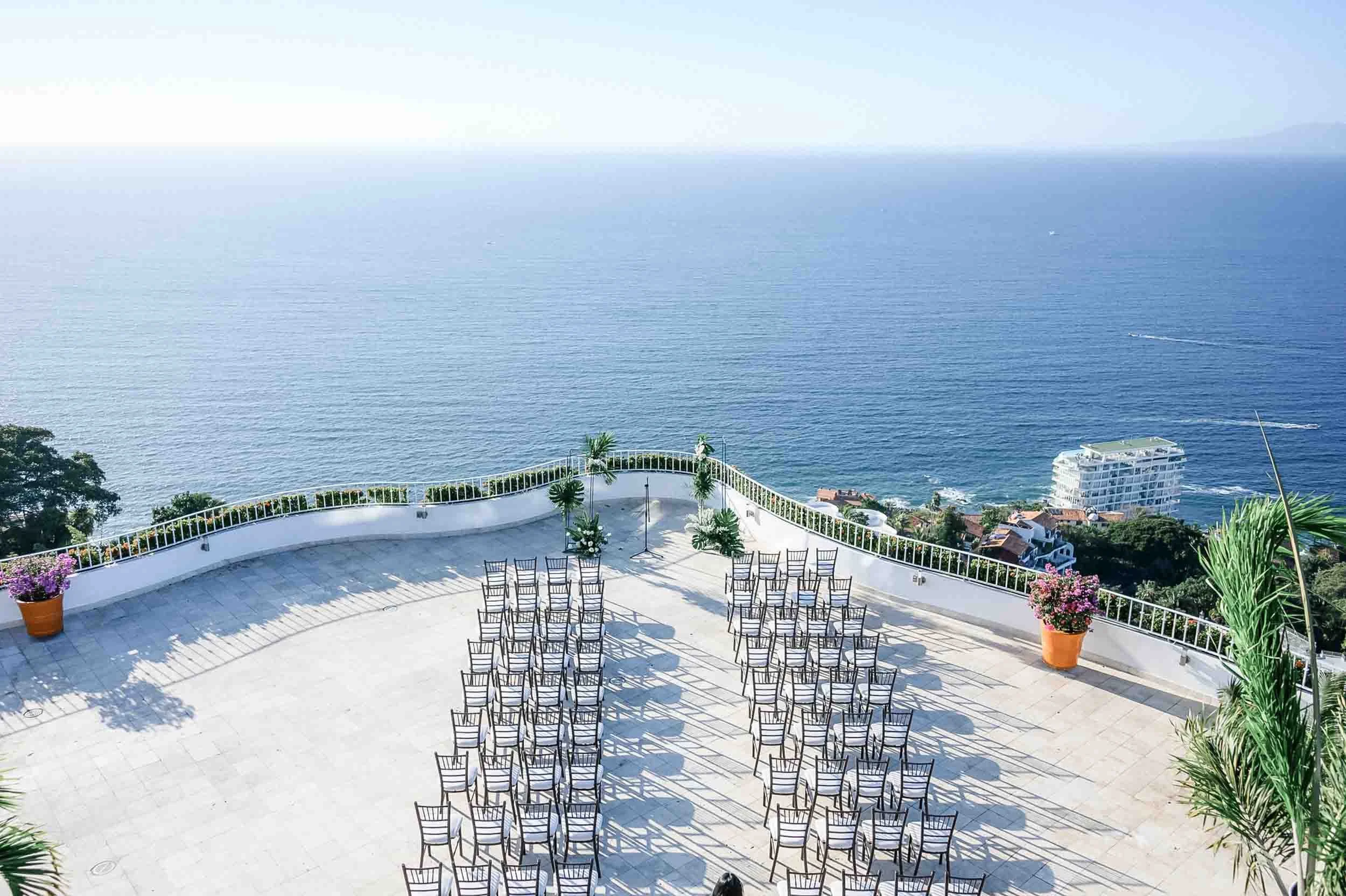 An outdoor ceremony space with rows of chairs arranged on a tiled terrace overlooking the ocean from the Grand Miramar resort.