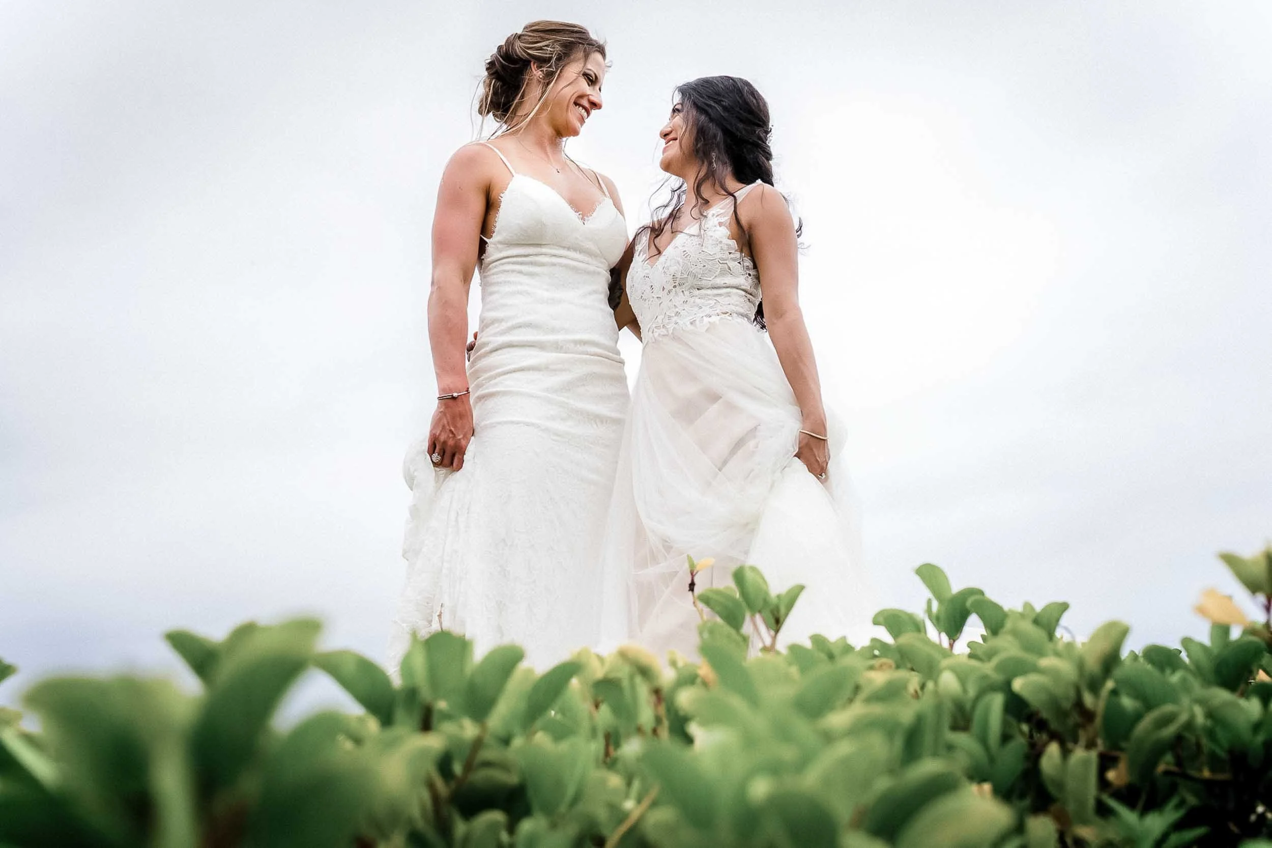 Beautiful lesbian brides posing for portraits at the beach at the Velas Resort in Puerto Vallarta Mexico