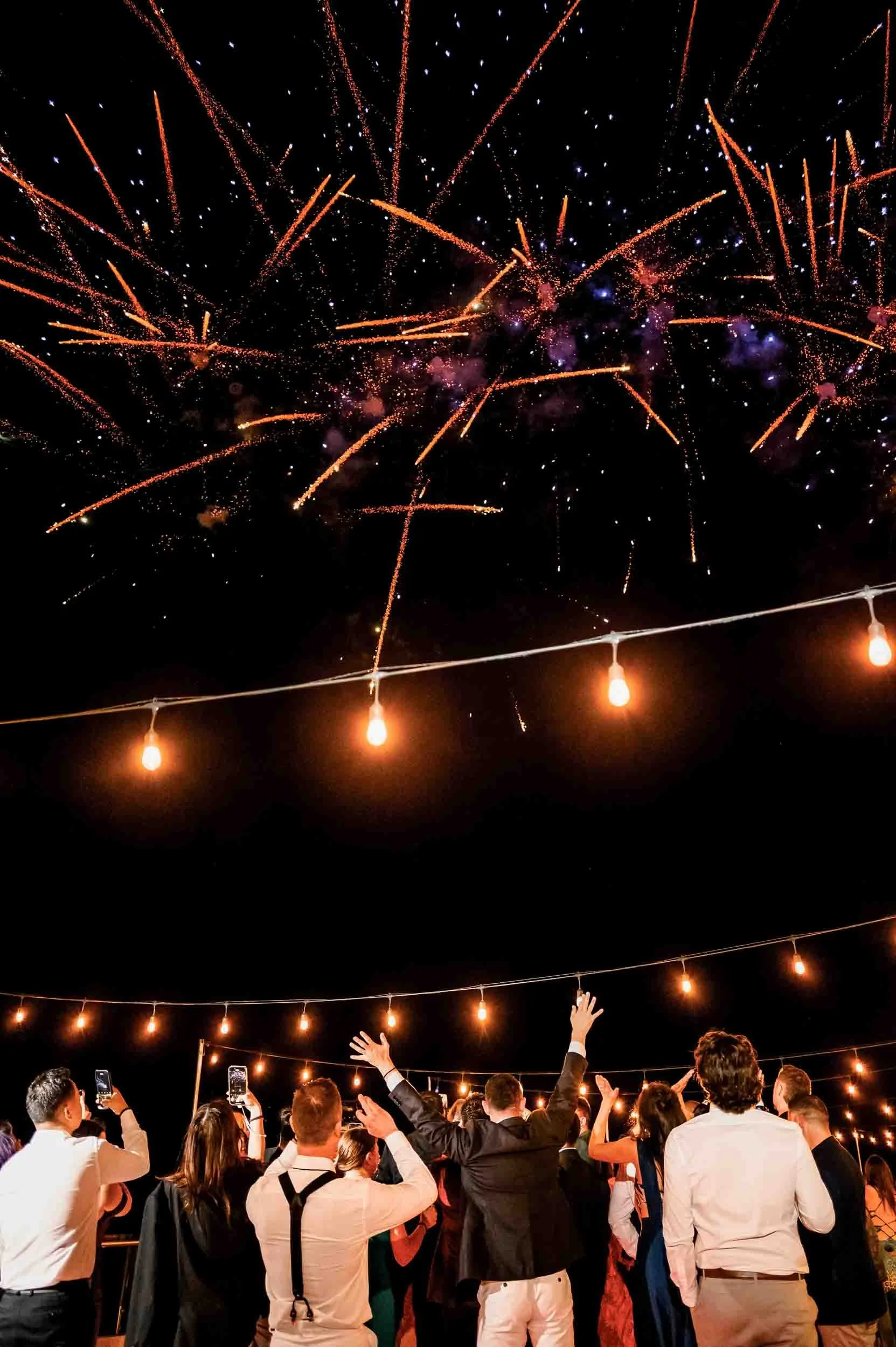 Wedding fireworks with grooms and guests on the dance floor during their wedding reception.