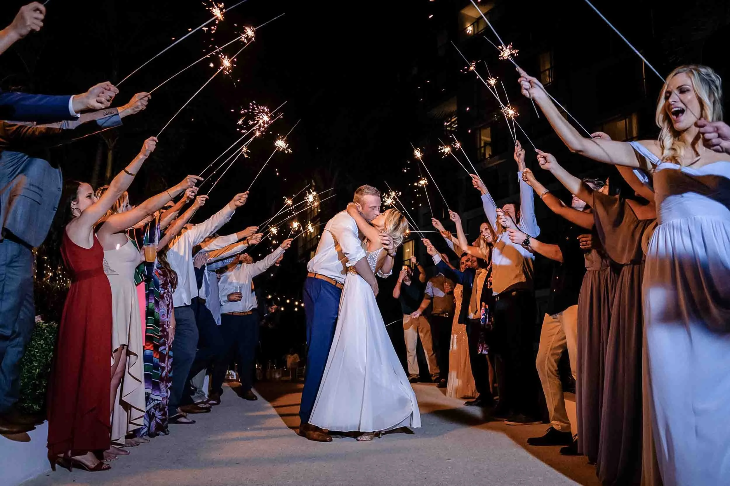 A sparkler exit from a wedding where the bride and groom share a kiss in the center.
