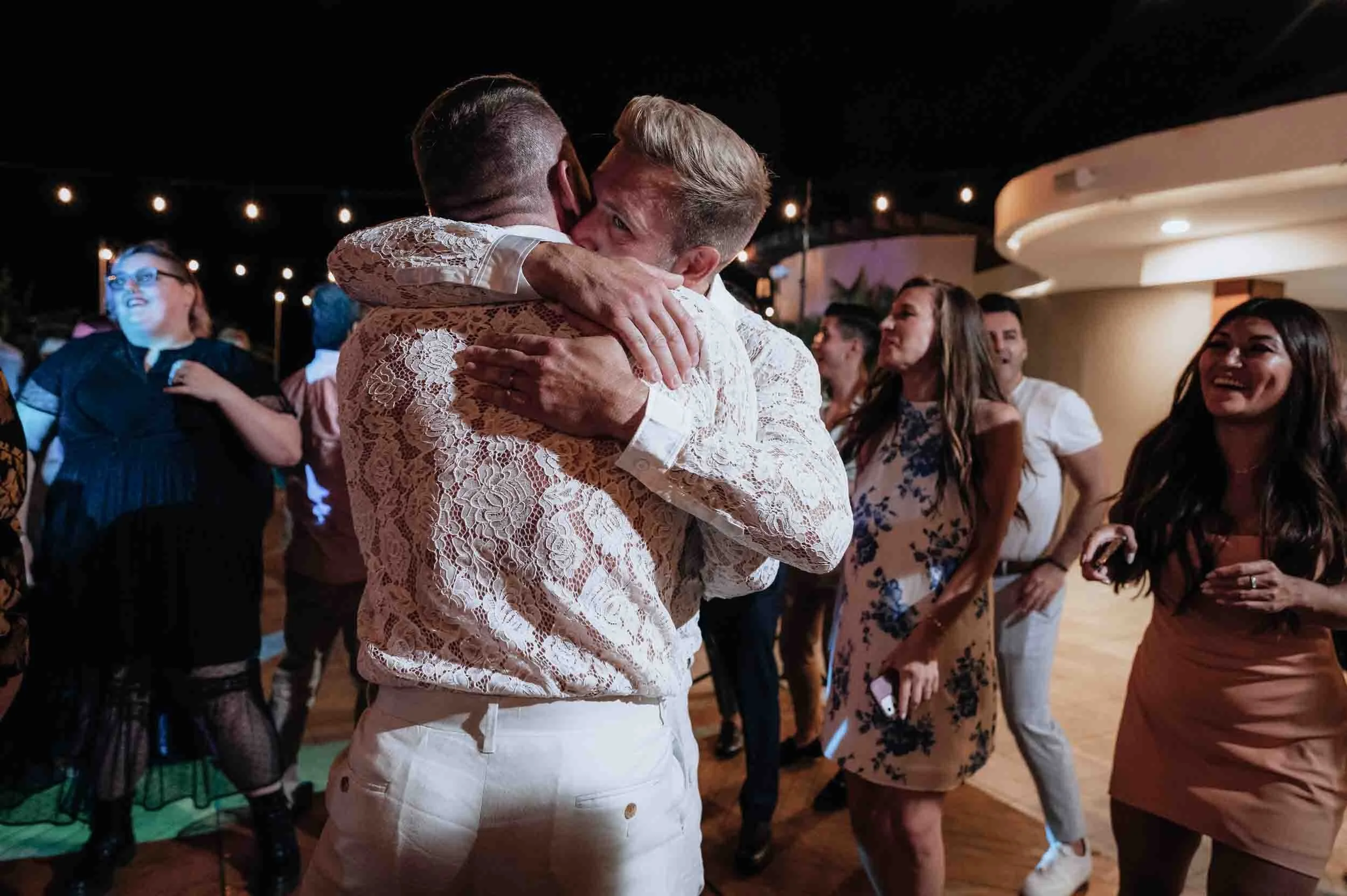 Grooms hugging each other while dancing during the reception of their wedding day.