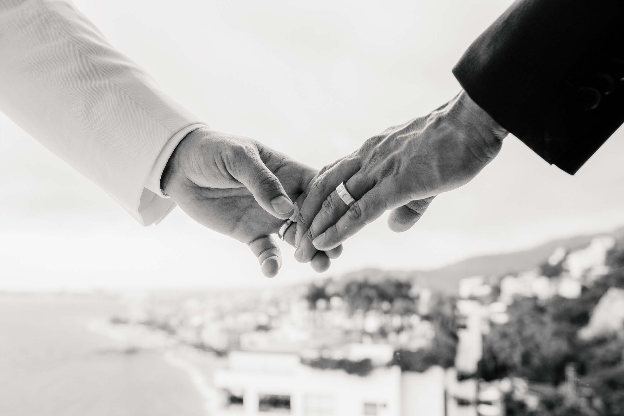 Detail of two grooms holding hands showing their wedding rings in Puerto Vallarta Mexico