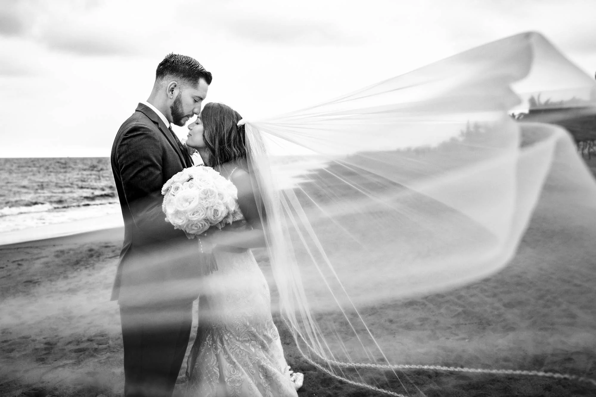 Wedding portrait at the beach with a flying veil.