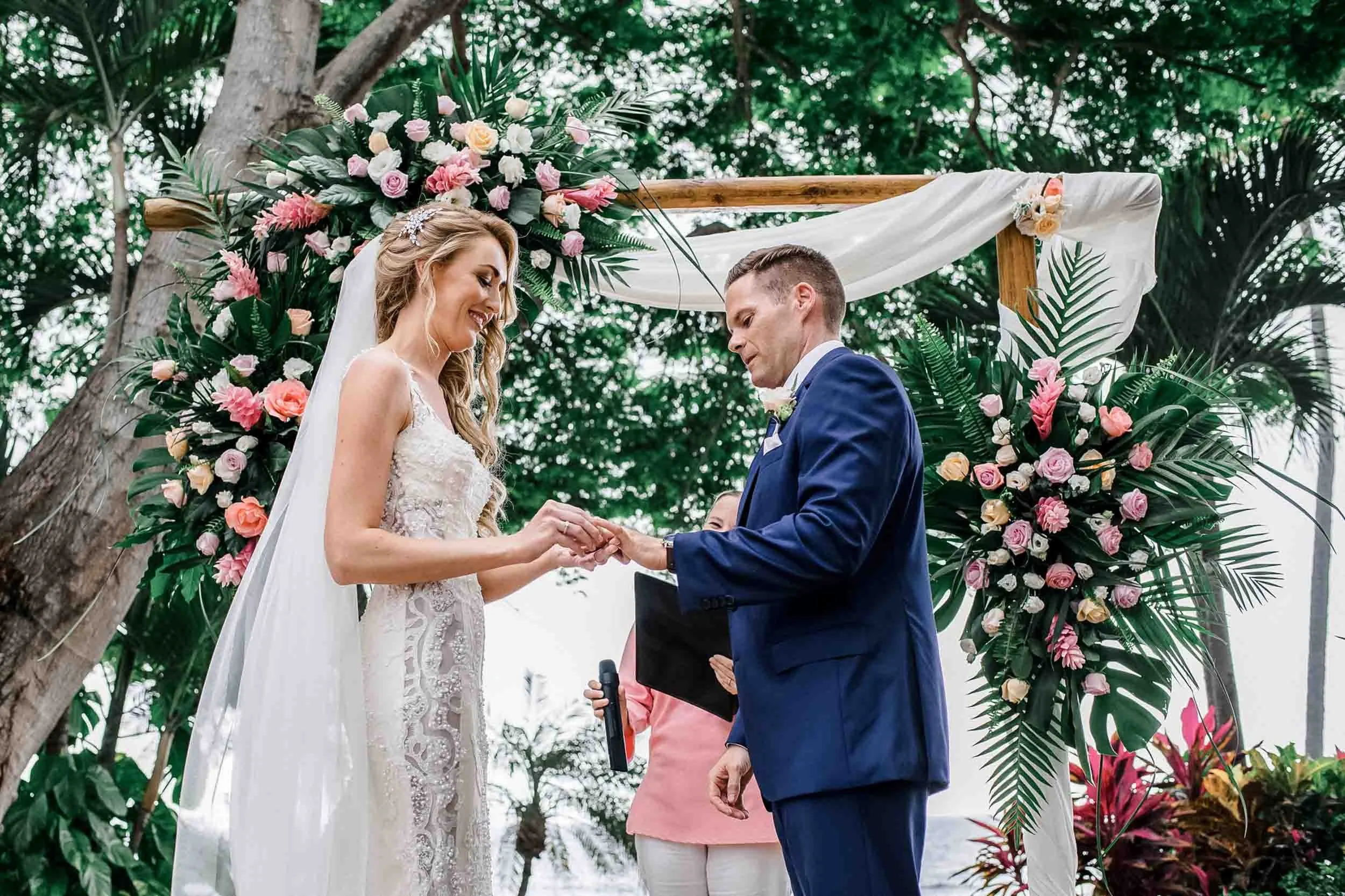A bride and groom exchanging rings during an outdoor wedding ceremony at the Hyatt Ziva resort.