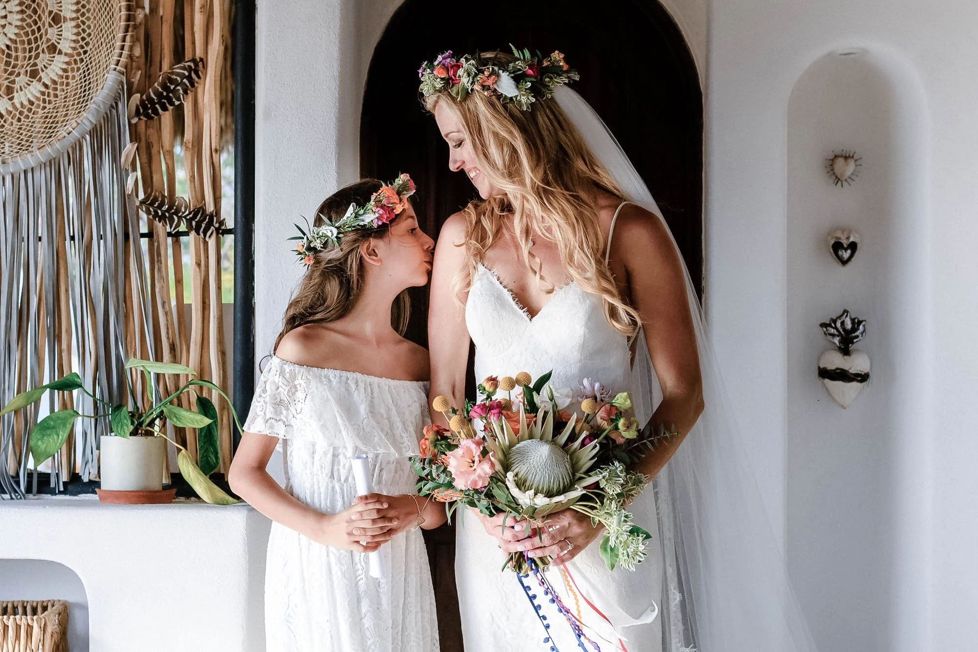 Daughter kissing bride before wedding ceremony.