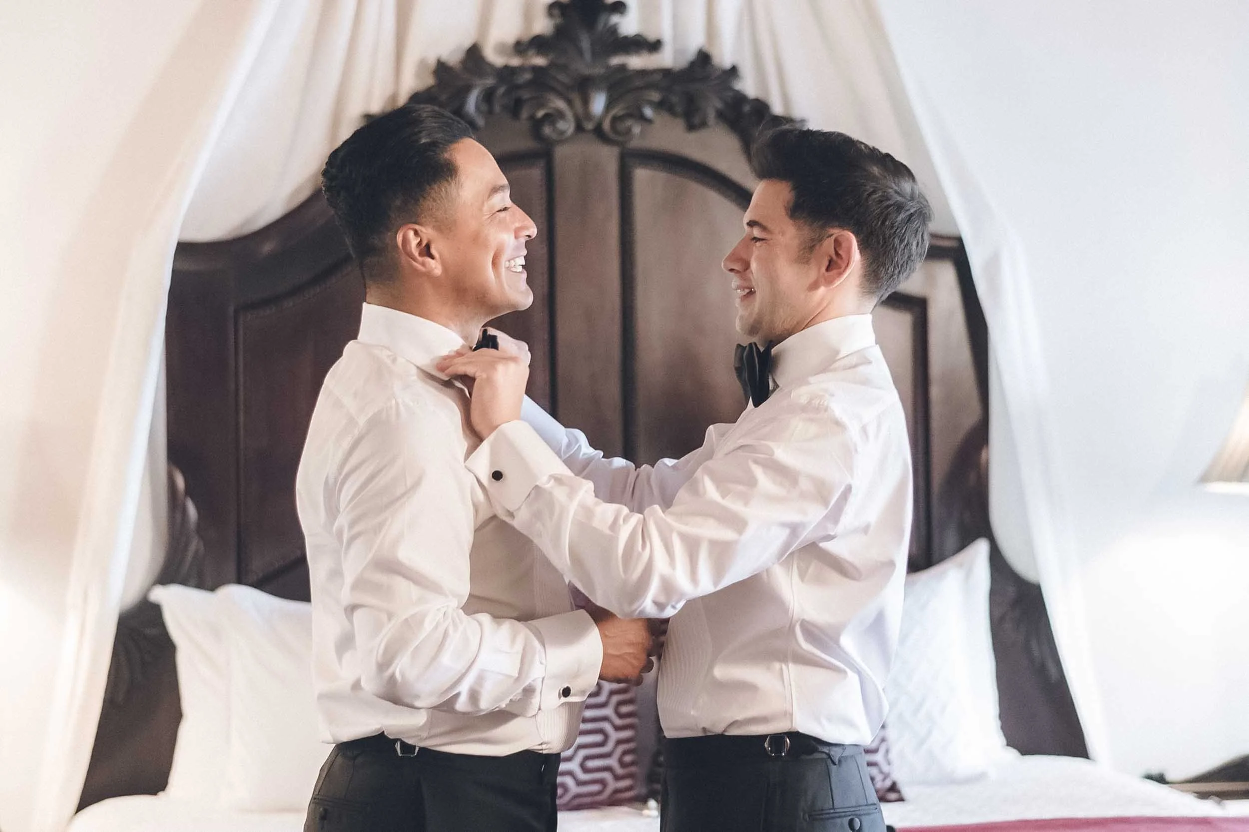 Gay couple  smiling and looking at each other while setting up each other's collars. They are sharing a joyful moment.