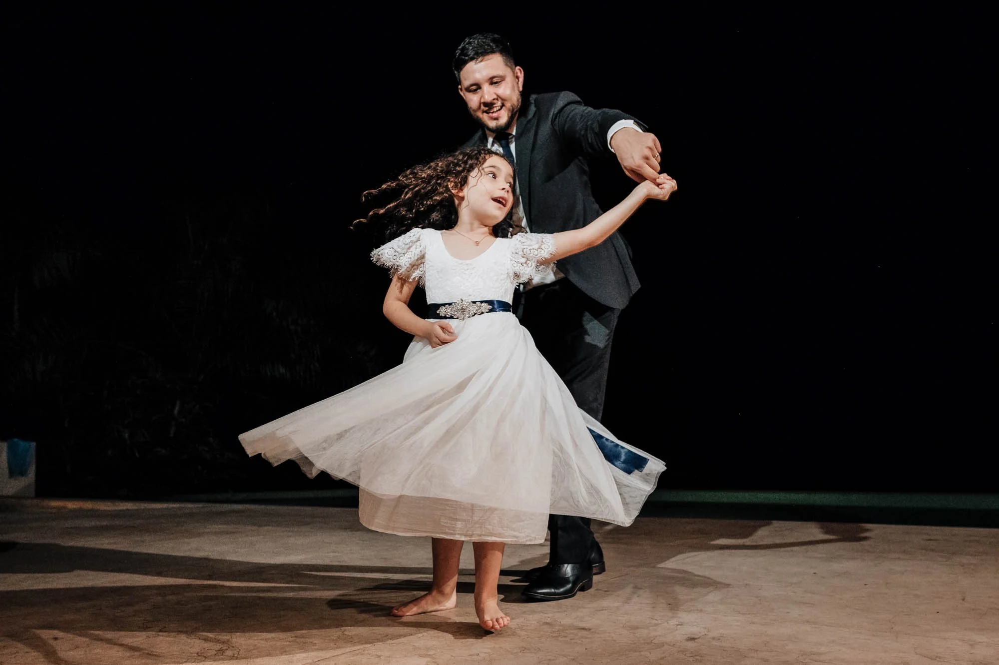 Groom dancing with flower girl at villa wedding.