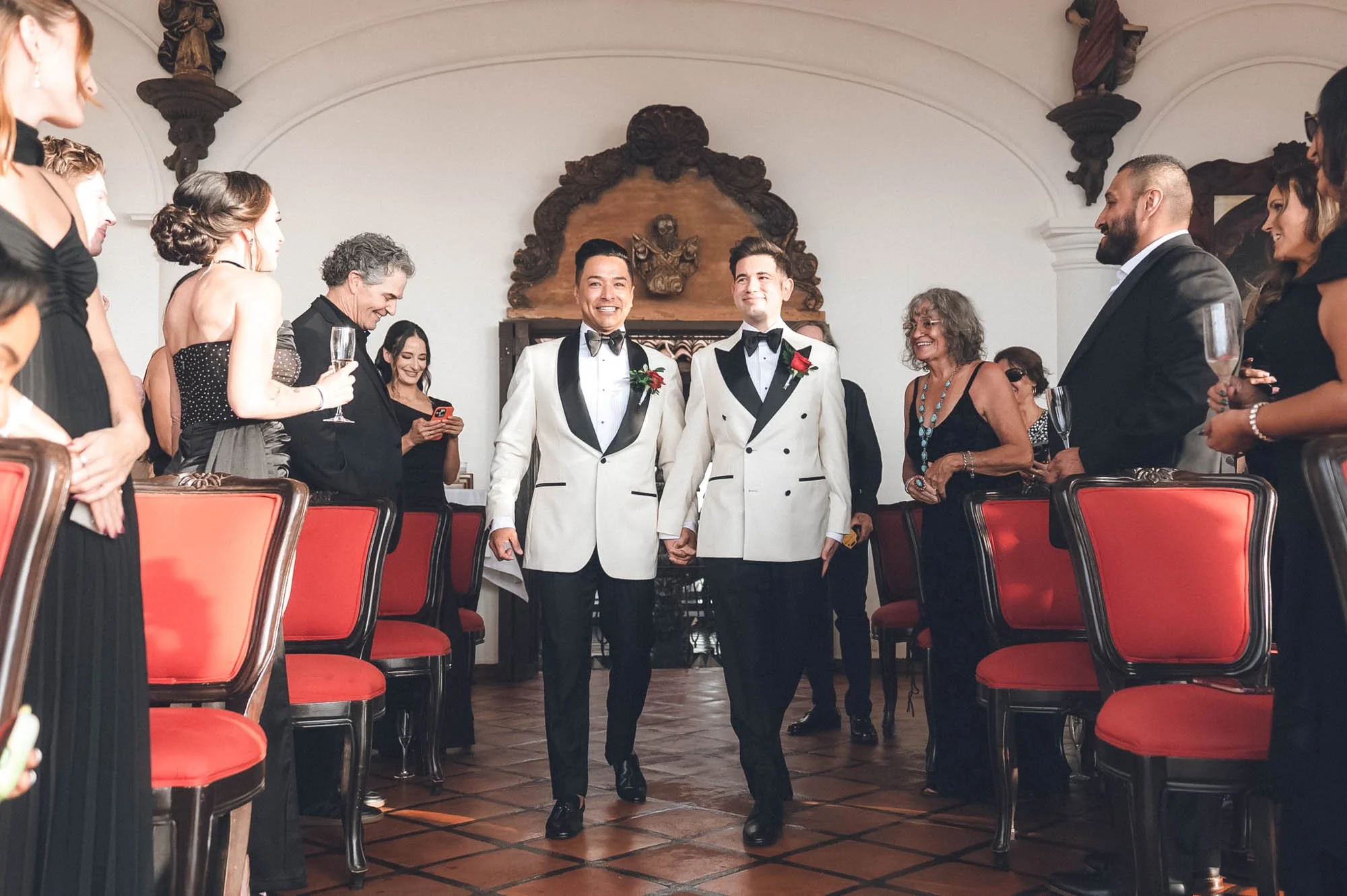 Grooms walking down an aisle entering their wedding ceremony at LGBTQ inclusive venue.