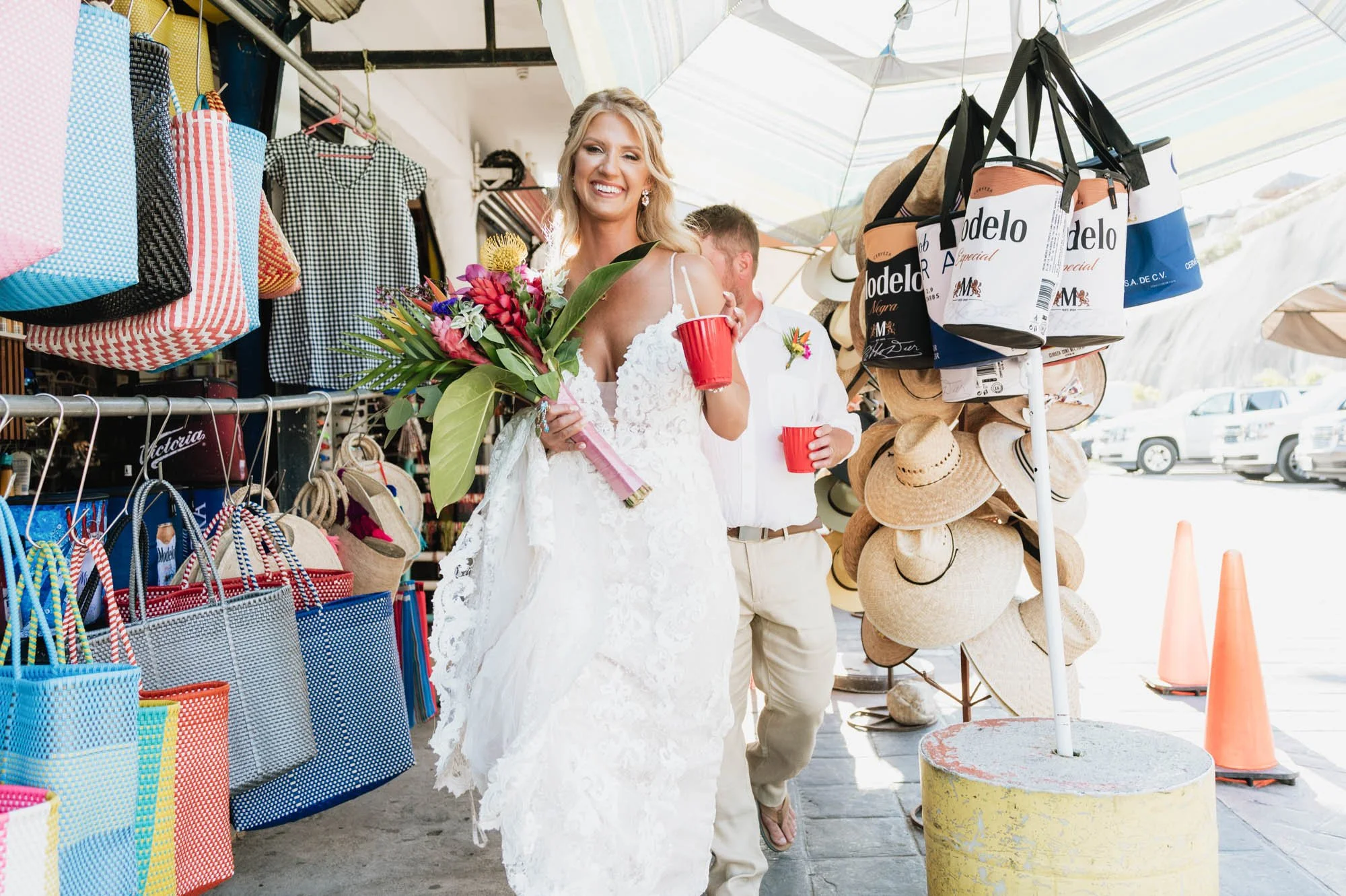 Bride walking on sidewalk after her wedding ceremony with a cold drink in her hand. 