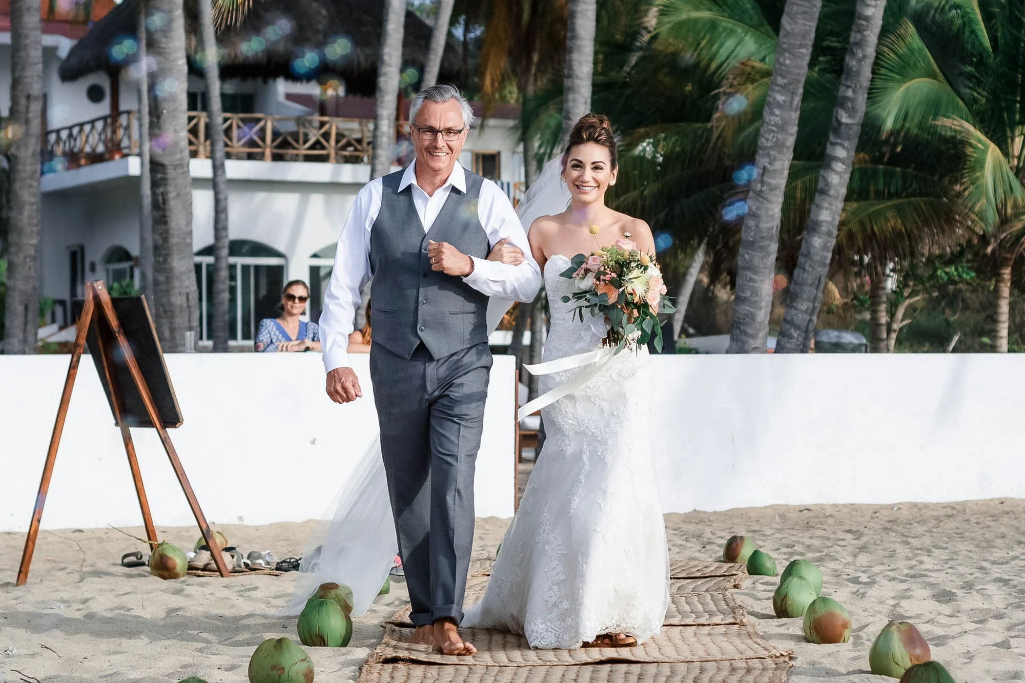 Father walks bride down the aisle at beach wedding.