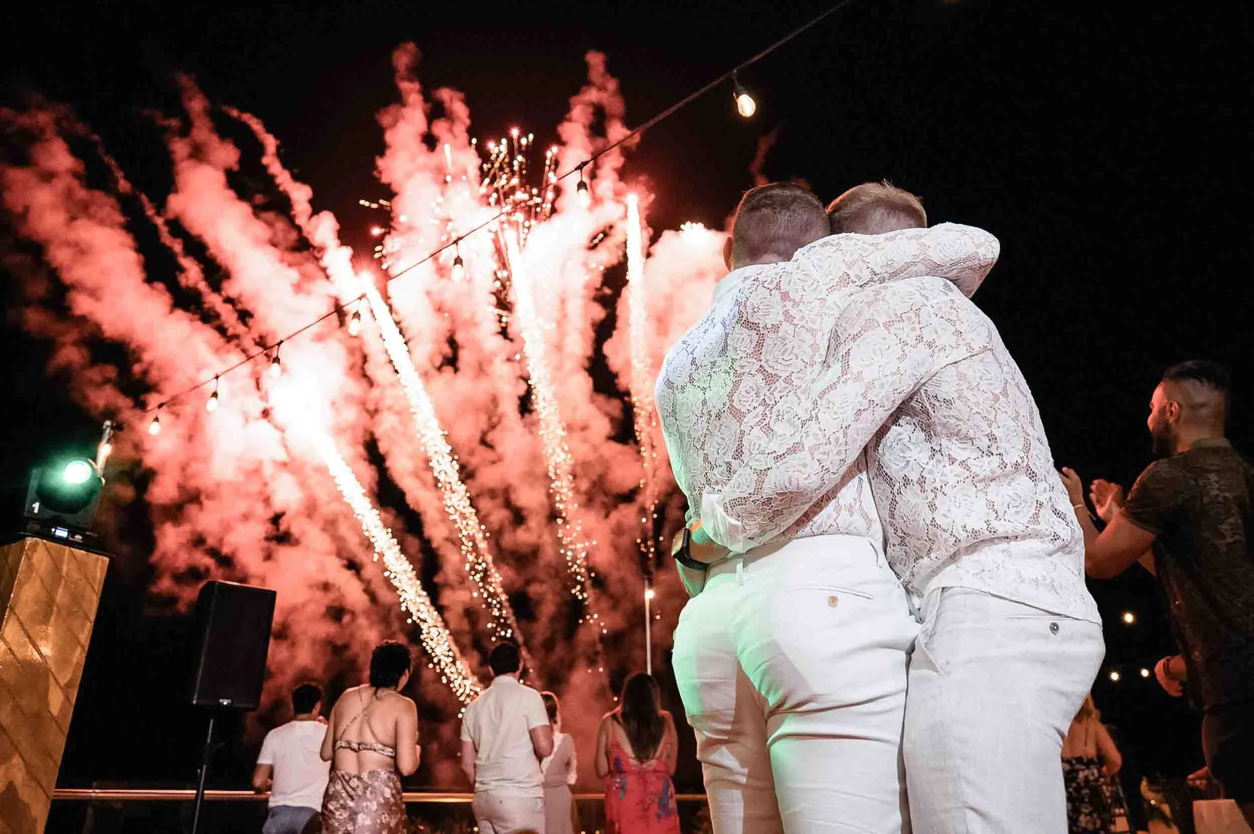 Surprise fireworks and grooms hugging during their wedding party at the luxury resort Grand Miramar in Puerto Vallarta
