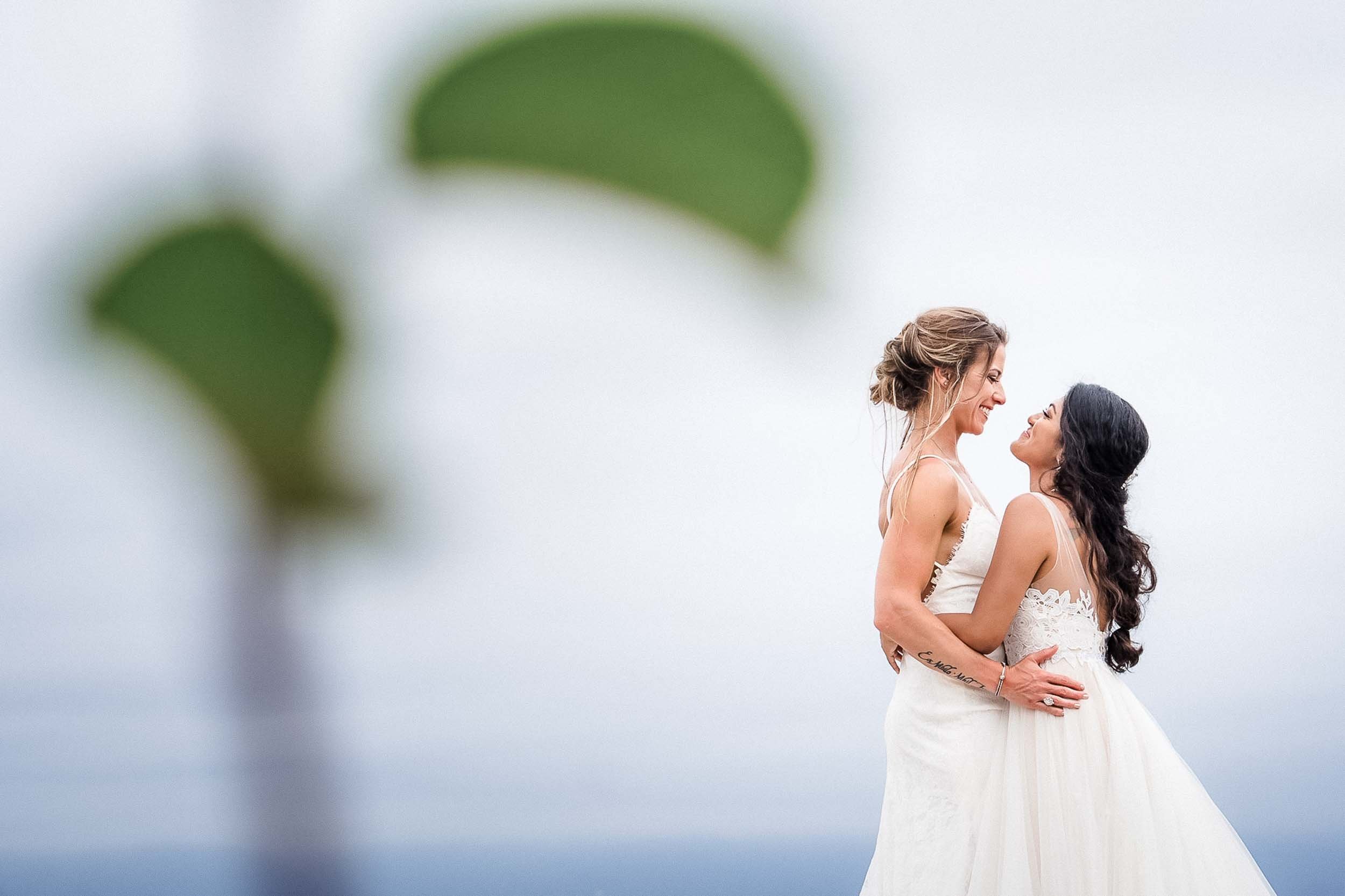 Lesbian couple happily posing on their wedding day at the beach of the Velas Resort in Puerto Vallarta